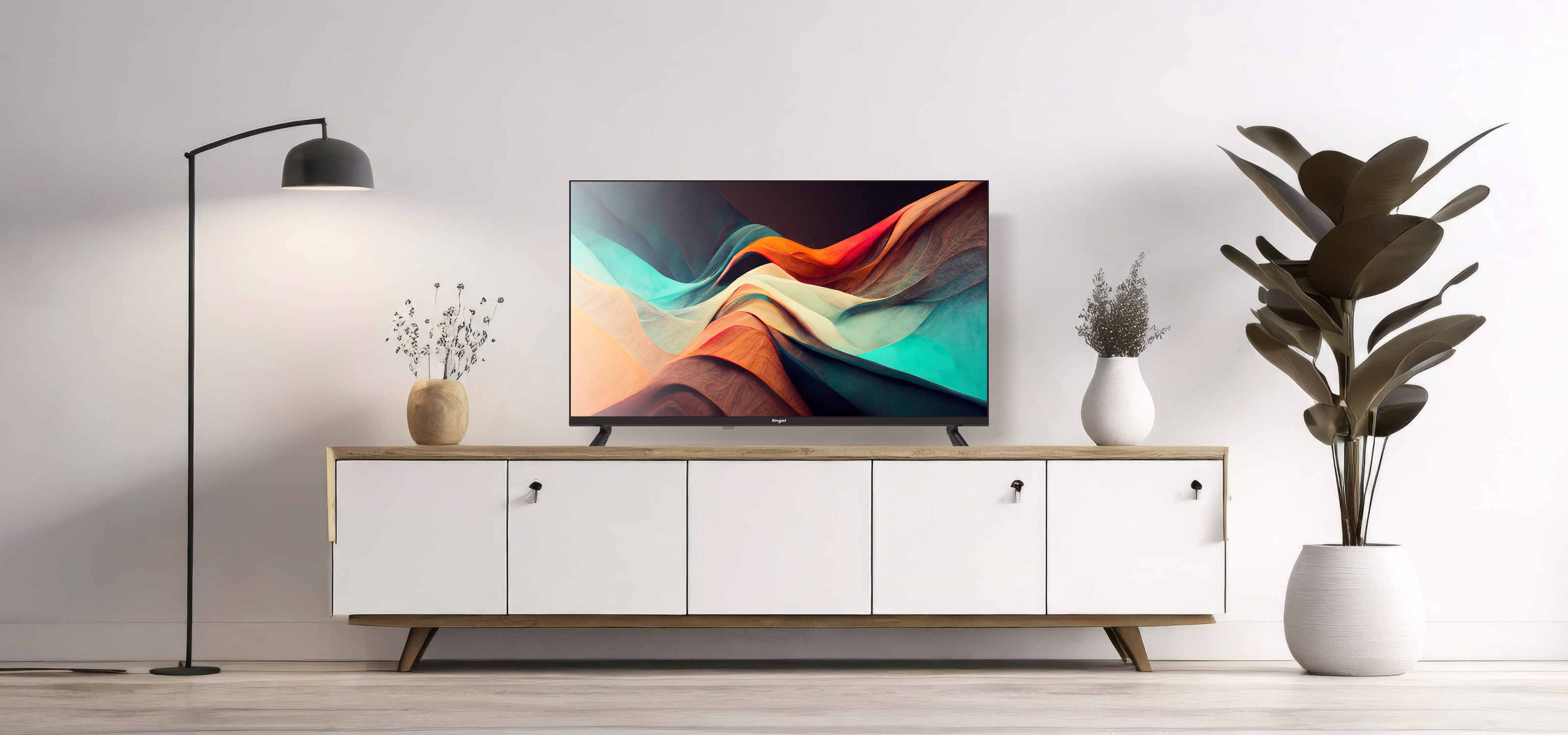 Nowoczesny salon z telewizorem na szafce, lampą podłogową i roślinami doniczkowymi. Białe ściany.