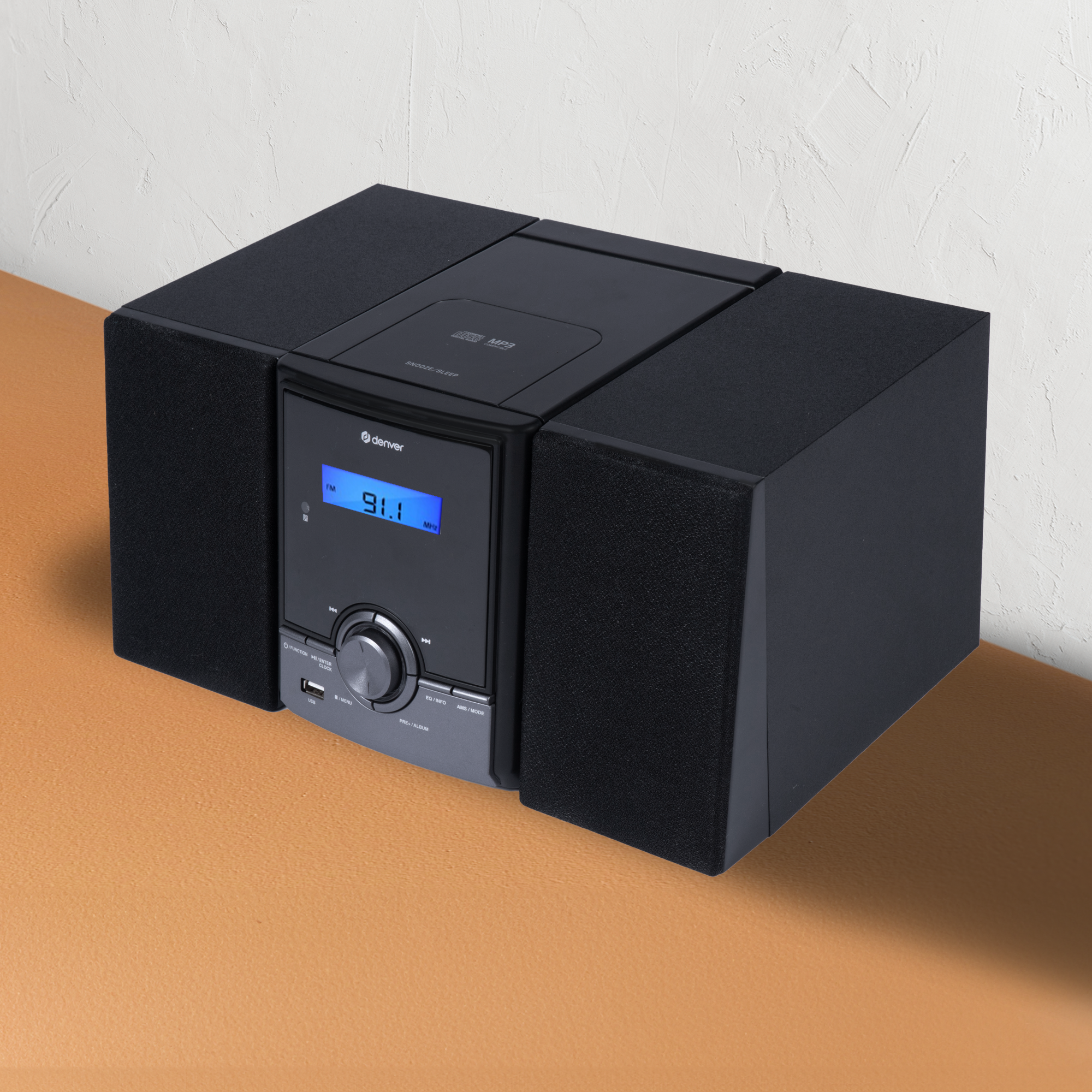 Czarny system audio z odtwarzaczem CD i głośnikami, na jasnobrązowej powierzchni.