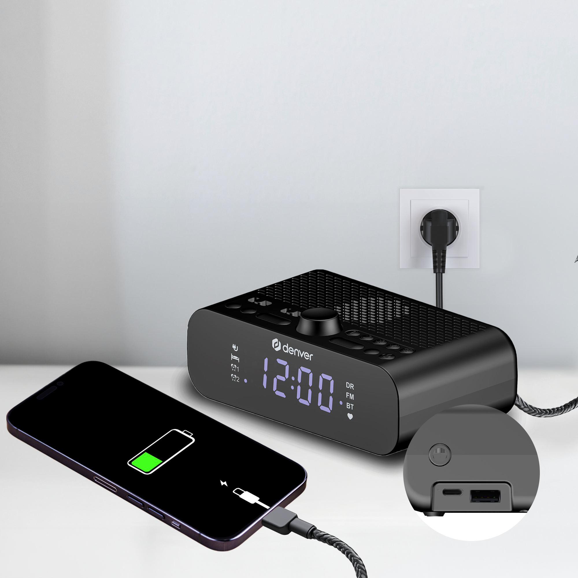 Schwarze Digitaluhr lädt ein schwarzes Telefon. Die Uhr zeigt die Zeit 12:00 Uhr an. Angeschlossen an eine weiße Steckdose.