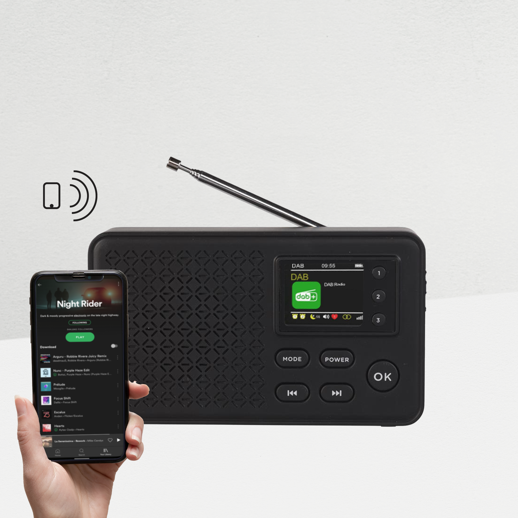 Czarne radio z telefonem pokazującym Spotify. Radio ma ekran i antenę. Telefon wyświetla muzykę.