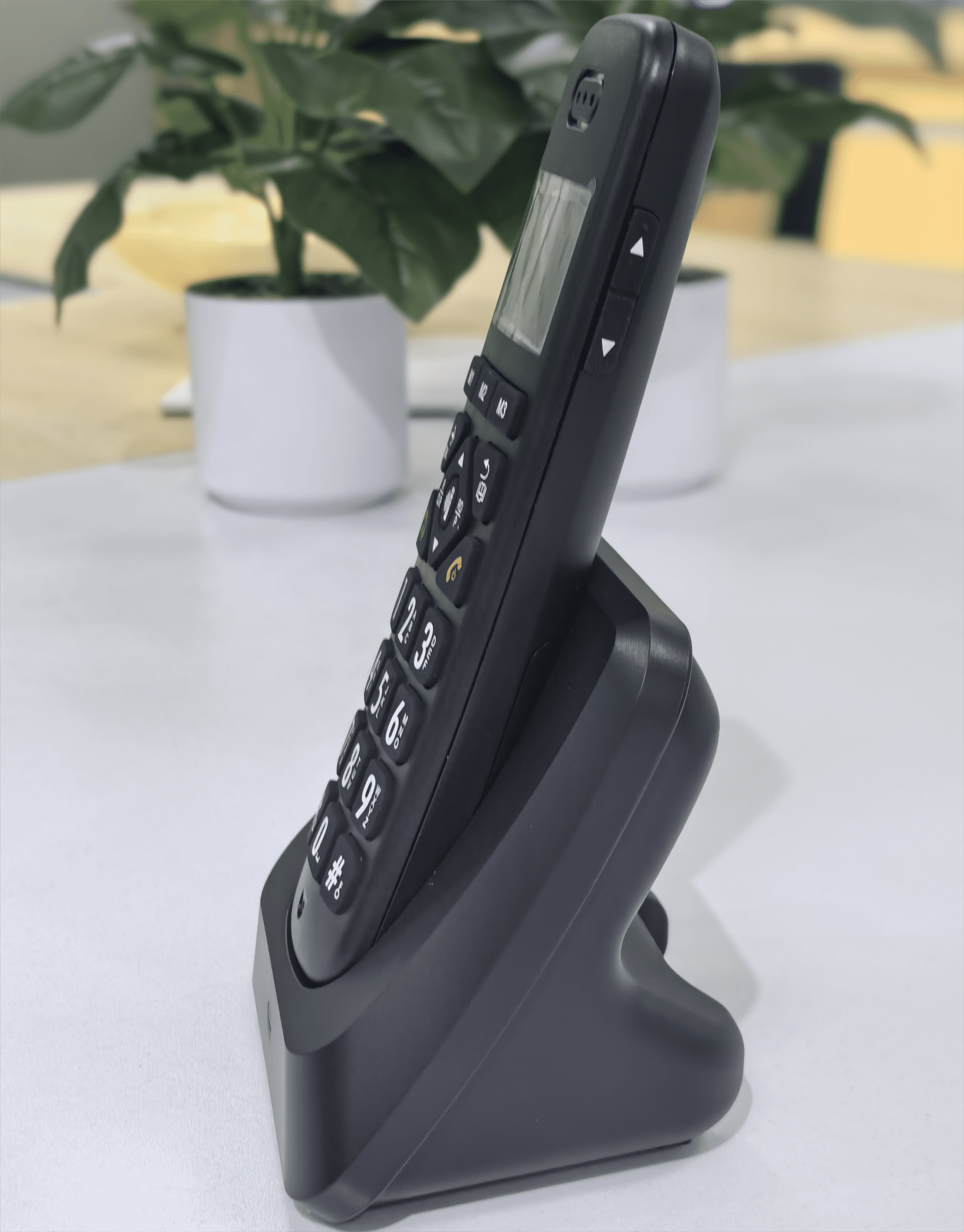 Schwarzes schnurloses Telefon mit Ladestation. Die Telefontasten sind sichtbar.