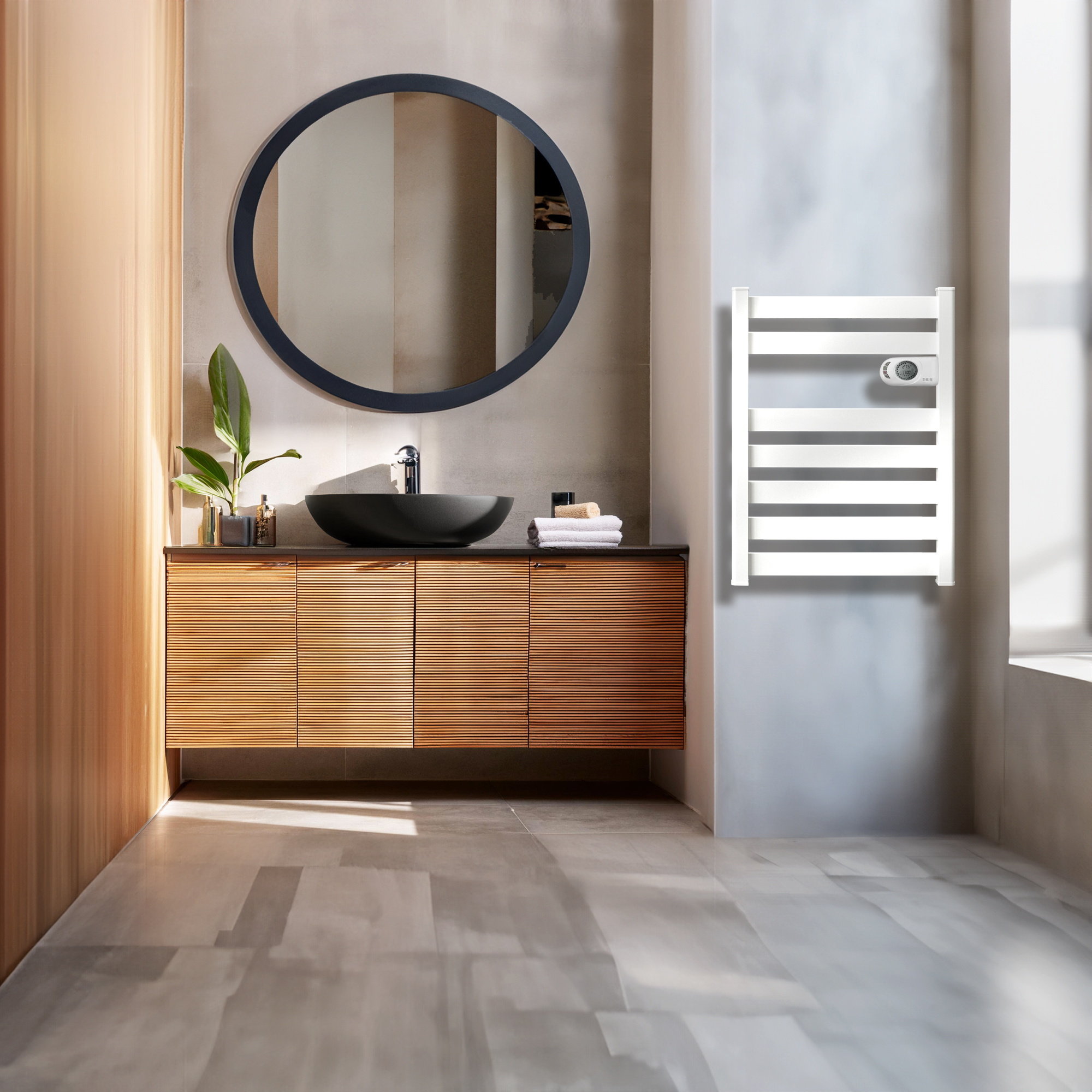 Baño moderno con lavabo negro, mueble de madera, espejo redondo y toallero térmico.