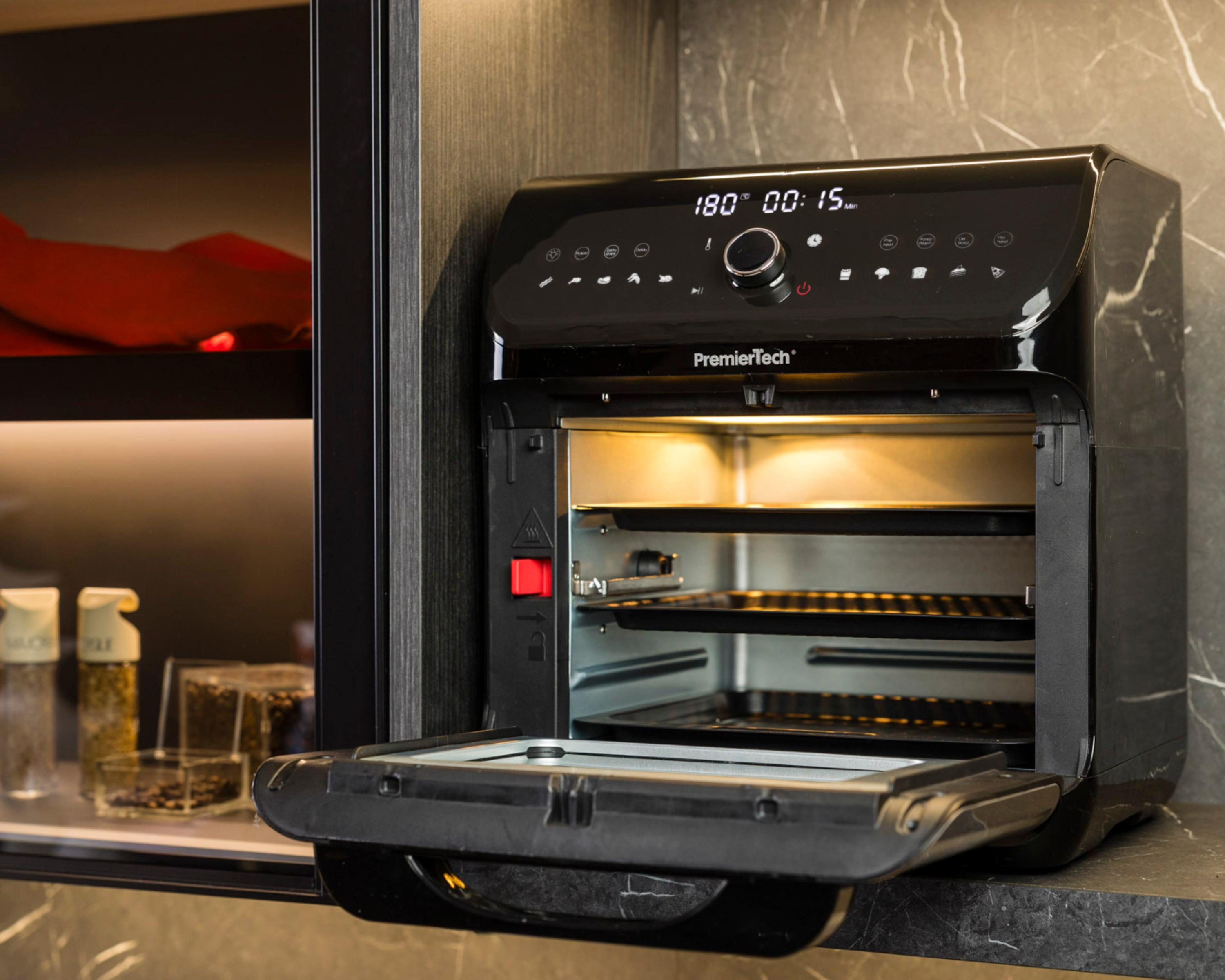 Friggitrice ad aria nera aperta, interno visibile con vassoi. In un mobile cucina.
