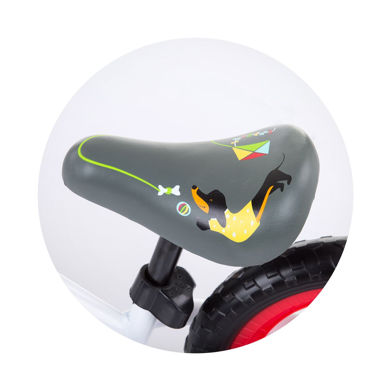 Un primer plano del asiento de una bicicleta de equilibrio. El asiento es gris con un dibujo de perro y una rueda roja.