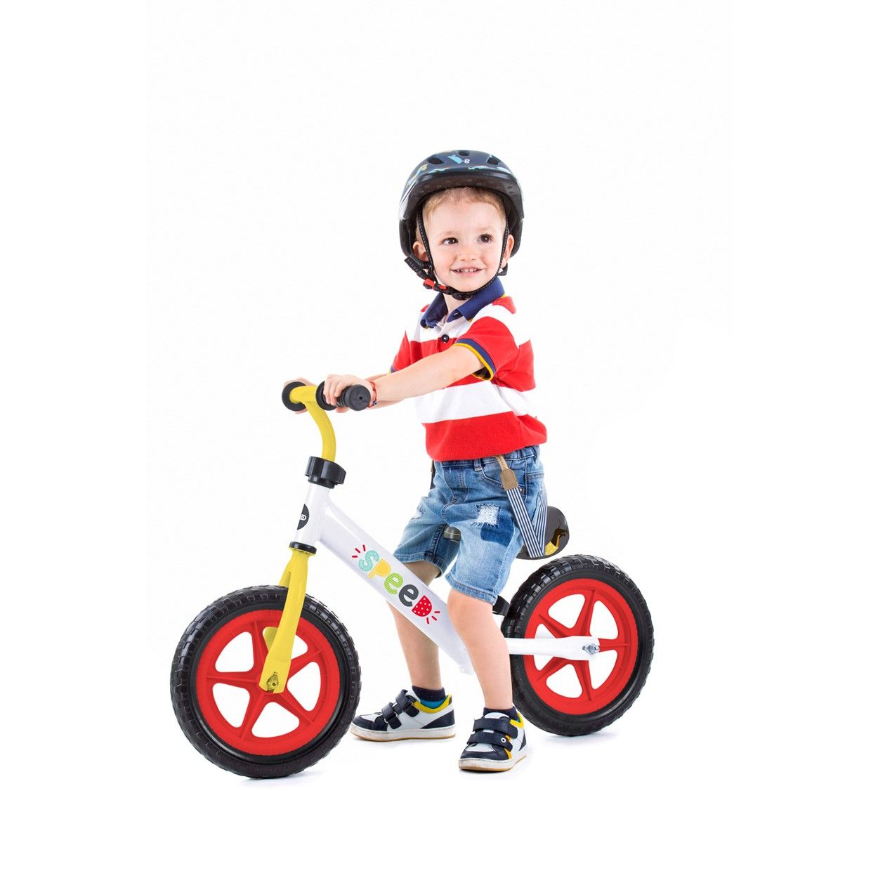 Un niño pequeño en una bicicleta de equilibrio con casco, sonriendo a la cámara.