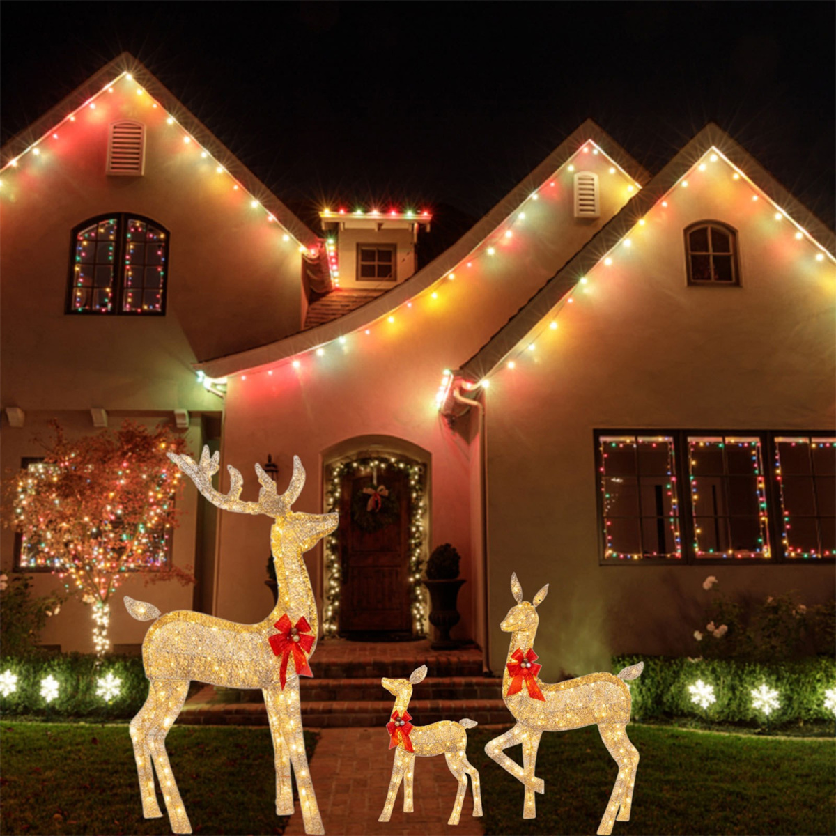 Ein Haus ist mit Weihnachtsbeleuchtung geschmückt. Es gibt drei Hirschstatuen mit roten Schleifen.