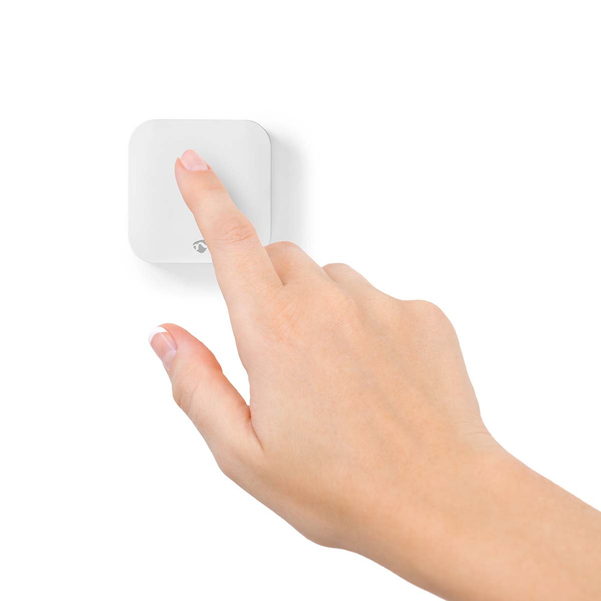 Een hand drukt op een witte vierkante knop op een witte muur. Focus op de hand en de knop.