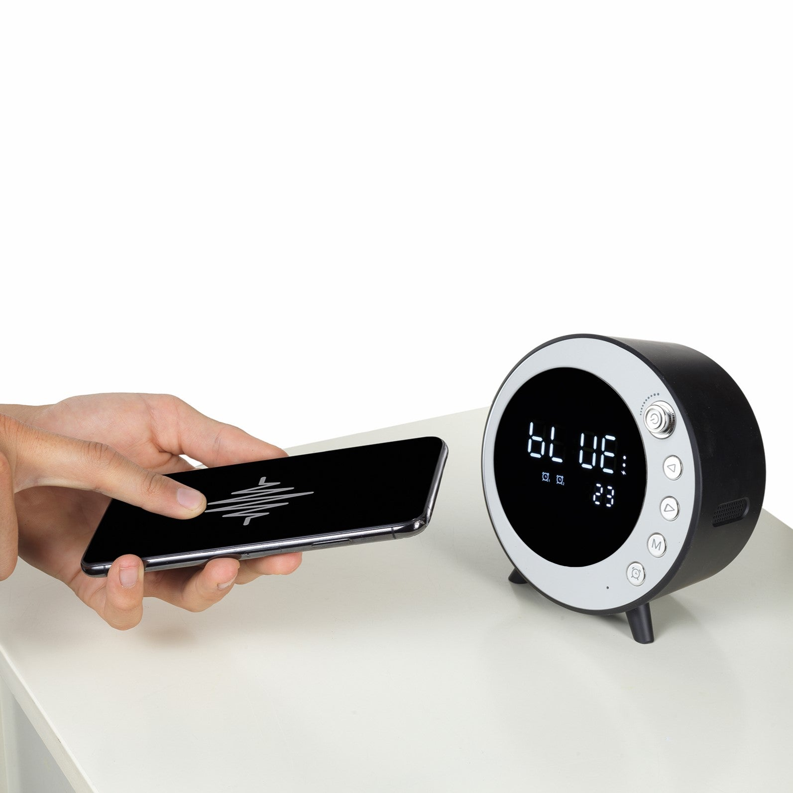Una mano interactuando con un smartphone, junto a un altavoz Bluetooth negro y plateado.