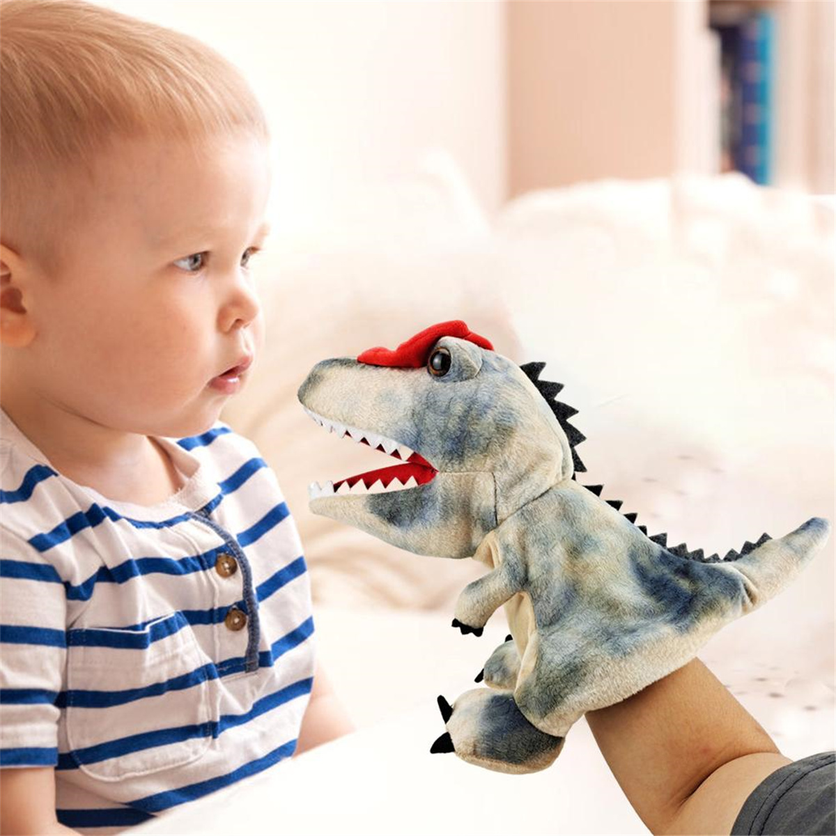 Ein Kind betrachtet eine Dinosaurier-Handpuppe, die von einer Person gehalten wird.