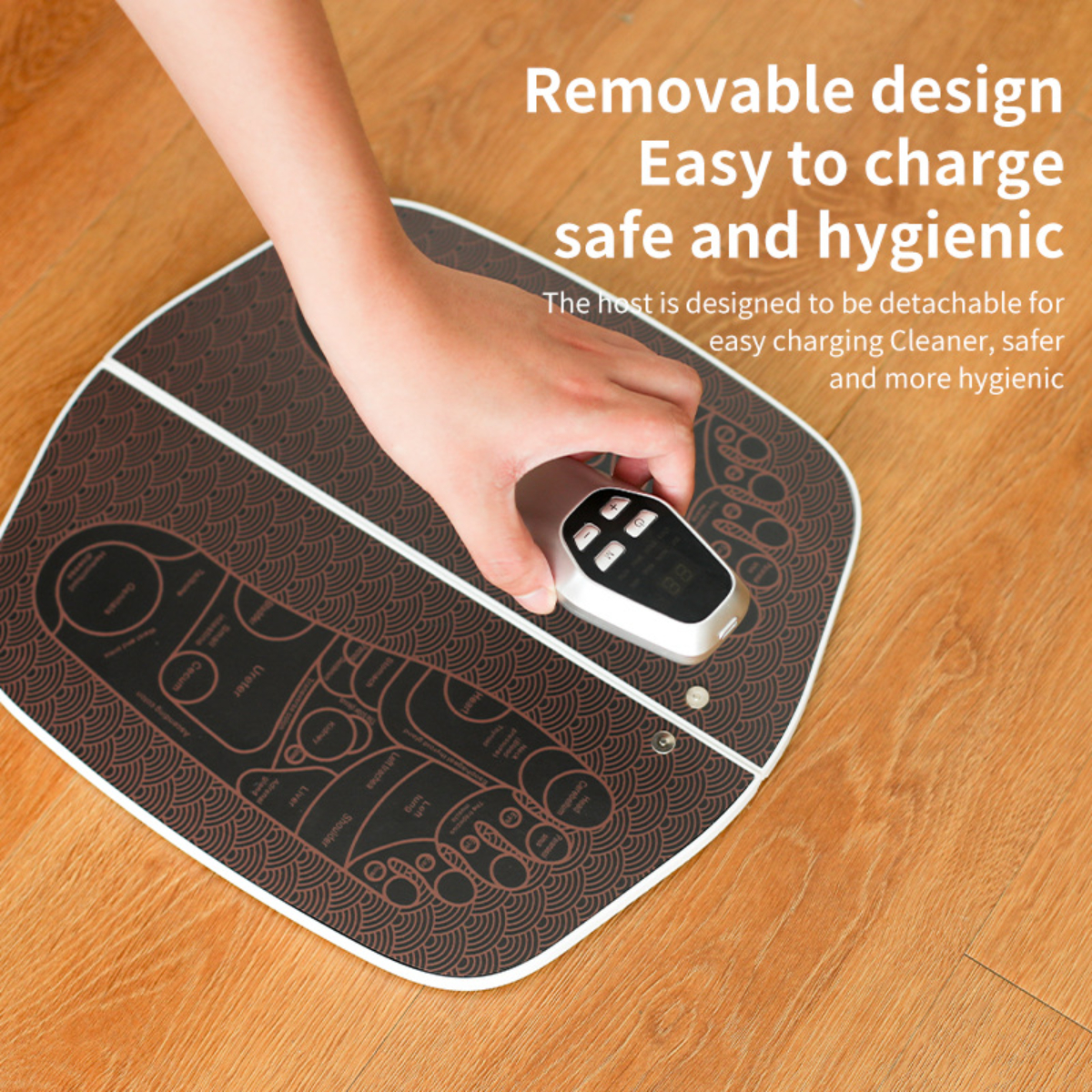 Die Hand einer Person hält eine Fernbedienung über einem Fußmassagepad mit Diagrammen und Text über Fußzonen.