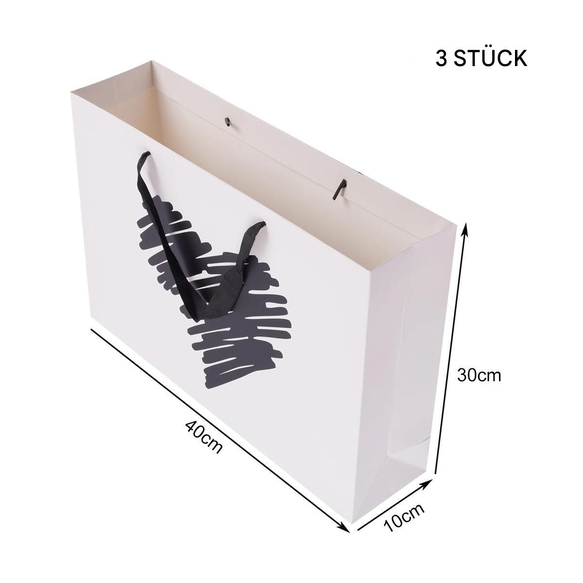 Drei weiße Papiereinkaufstüten mit schwarzem, abstraktem Design auf weißem Hintergrund.