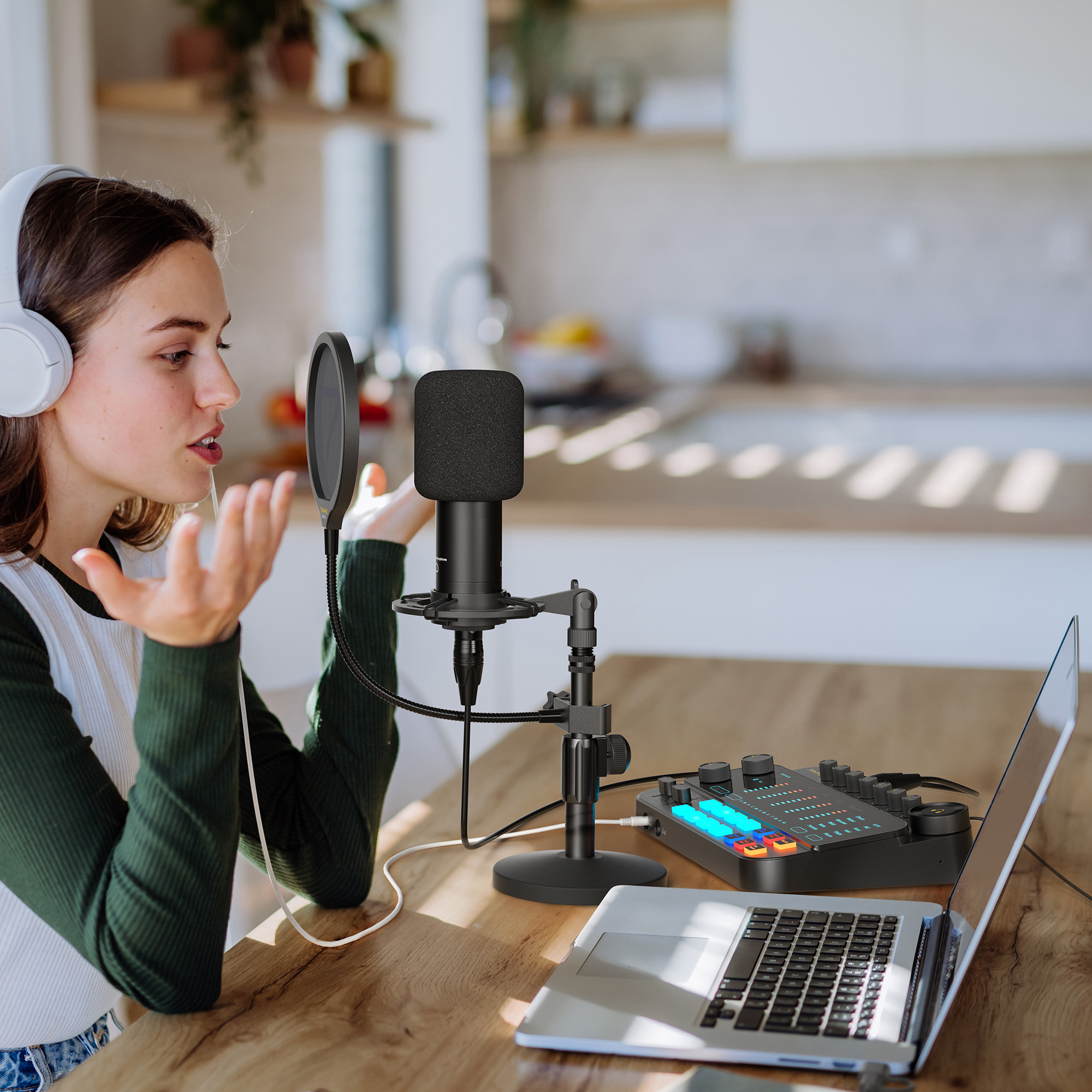 Een vrouw spreekt in een microfoon. Een laptop en een audiomixer staan voor haar.