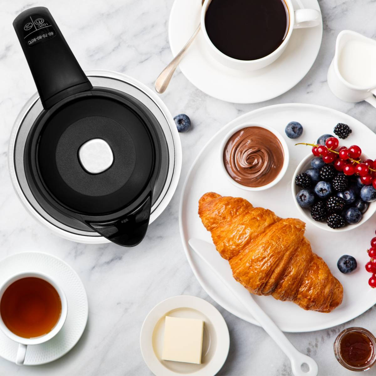 Overhead shot of food items like croissant, coffee, and berries.