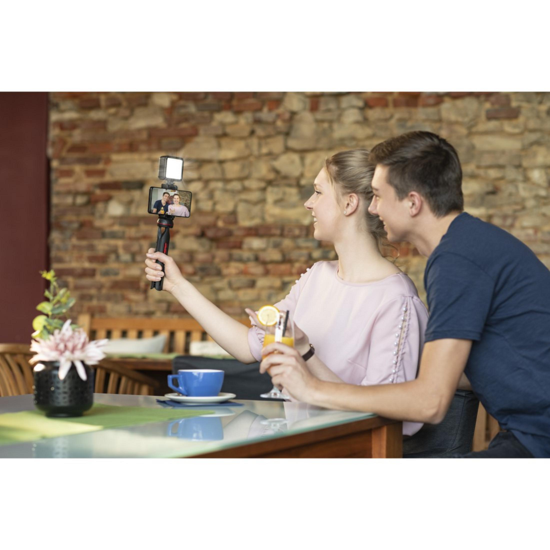 Paar macht Selfie mit Handy am Selfie-Stick im Freien.