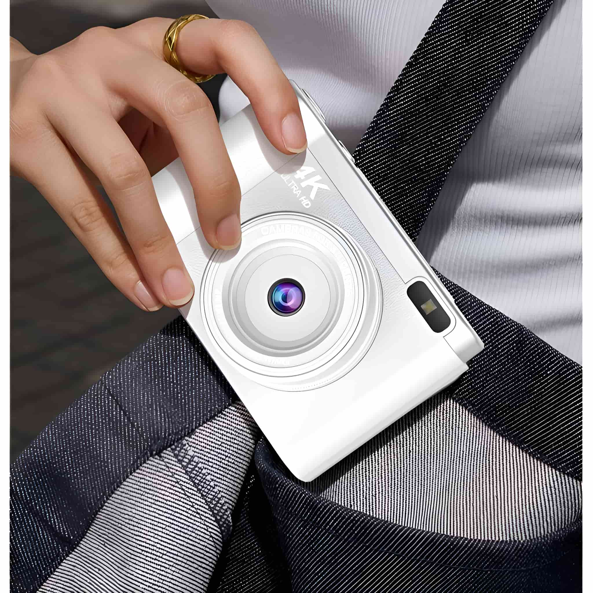 Eine weiße Digitalkamera, beschriftet mit '4K Ultra HD', wird von einer Hand über einer Tasche gehalten.
