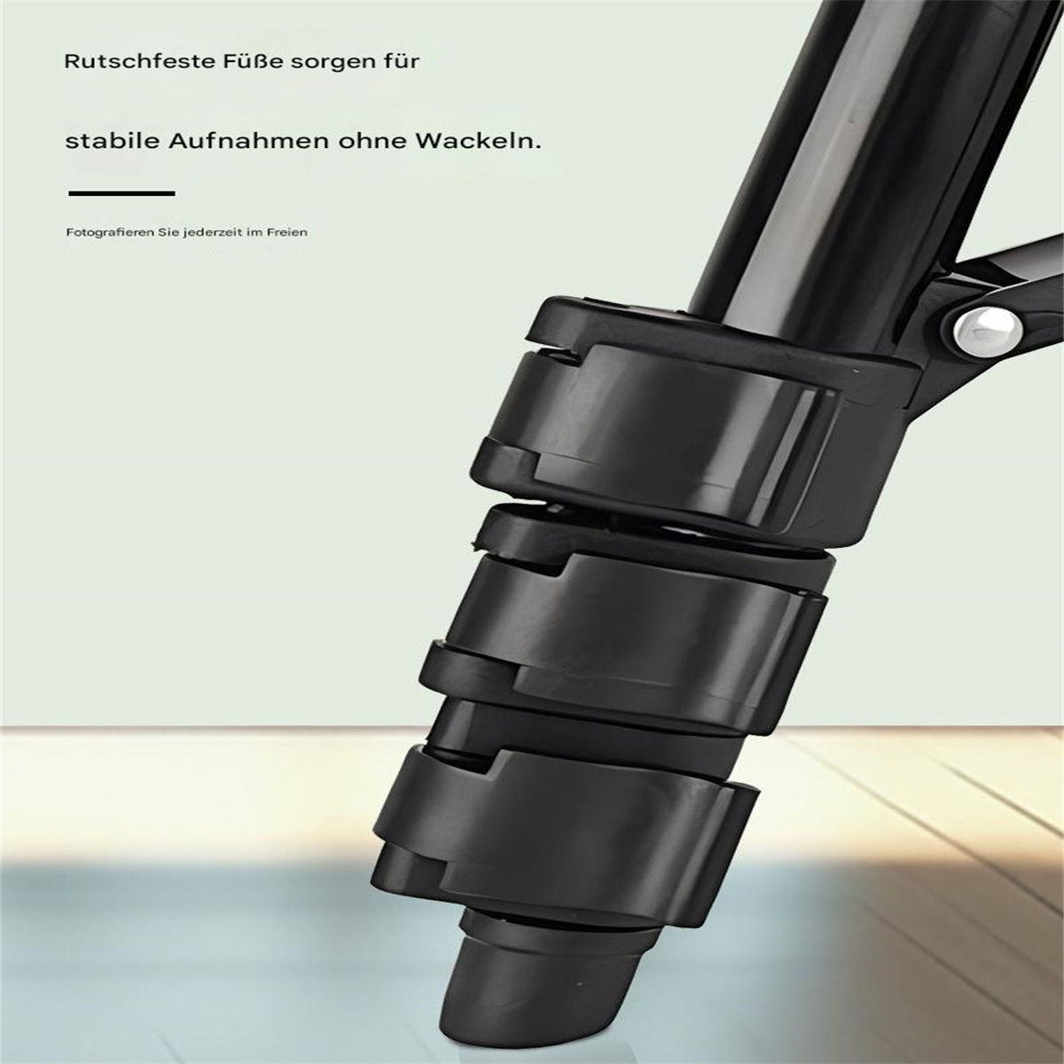 Nahaufnahme eines Stativbeins. Schwarz, segmentiert, mit Verriegelungsmechanismus. Der Hintergrund ist unscharf.