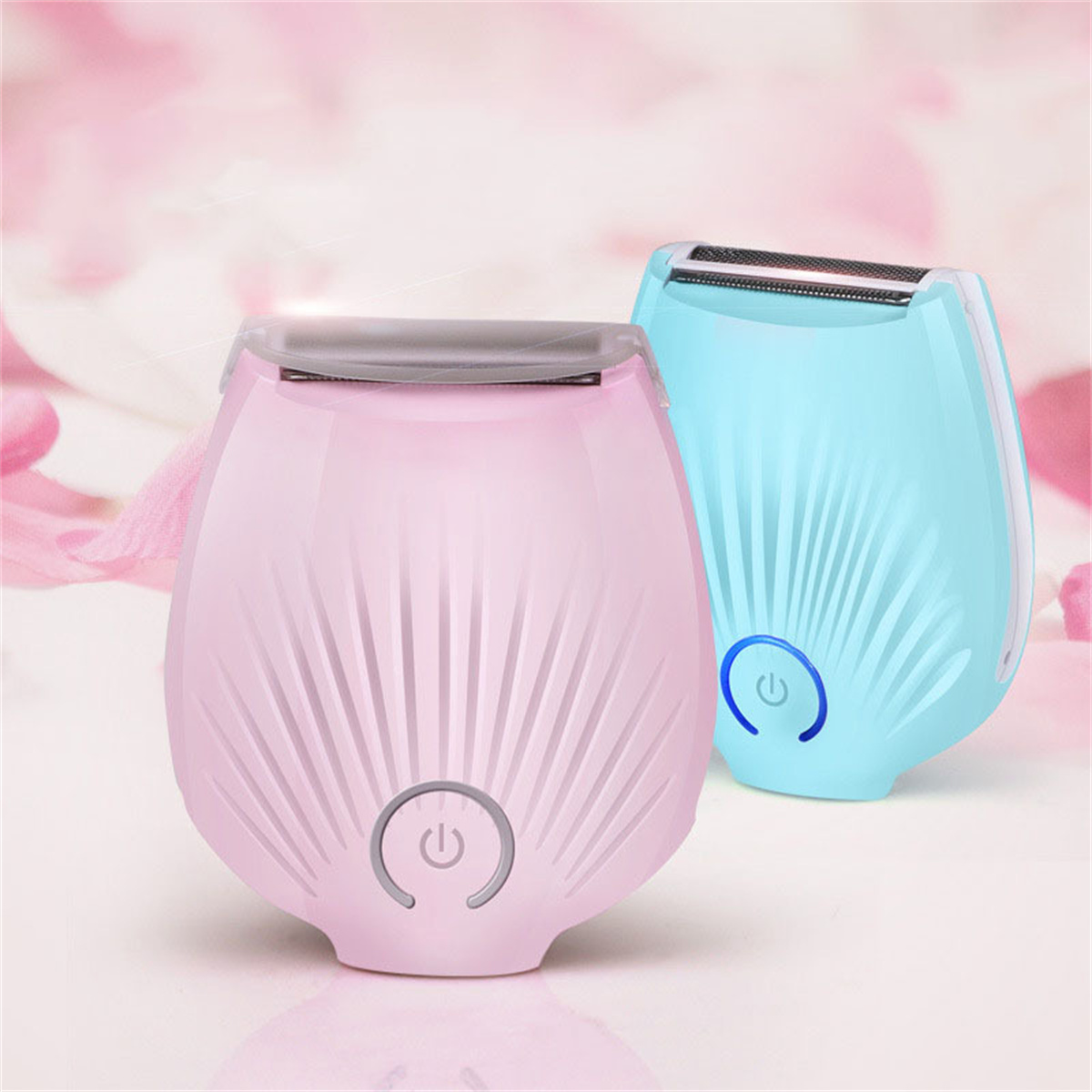 Zwei elektrische Rasierer, einer pink, einer blau, auf verschwommenem pinkem Hintergrund.