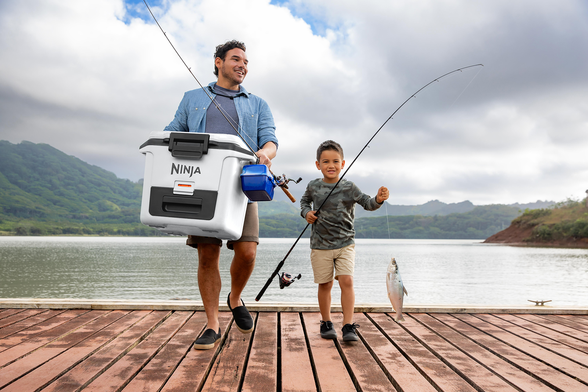 Mężczyzna i chłopiec na pomoście, łowiący z chłodziarką. Ryba została złowiona.