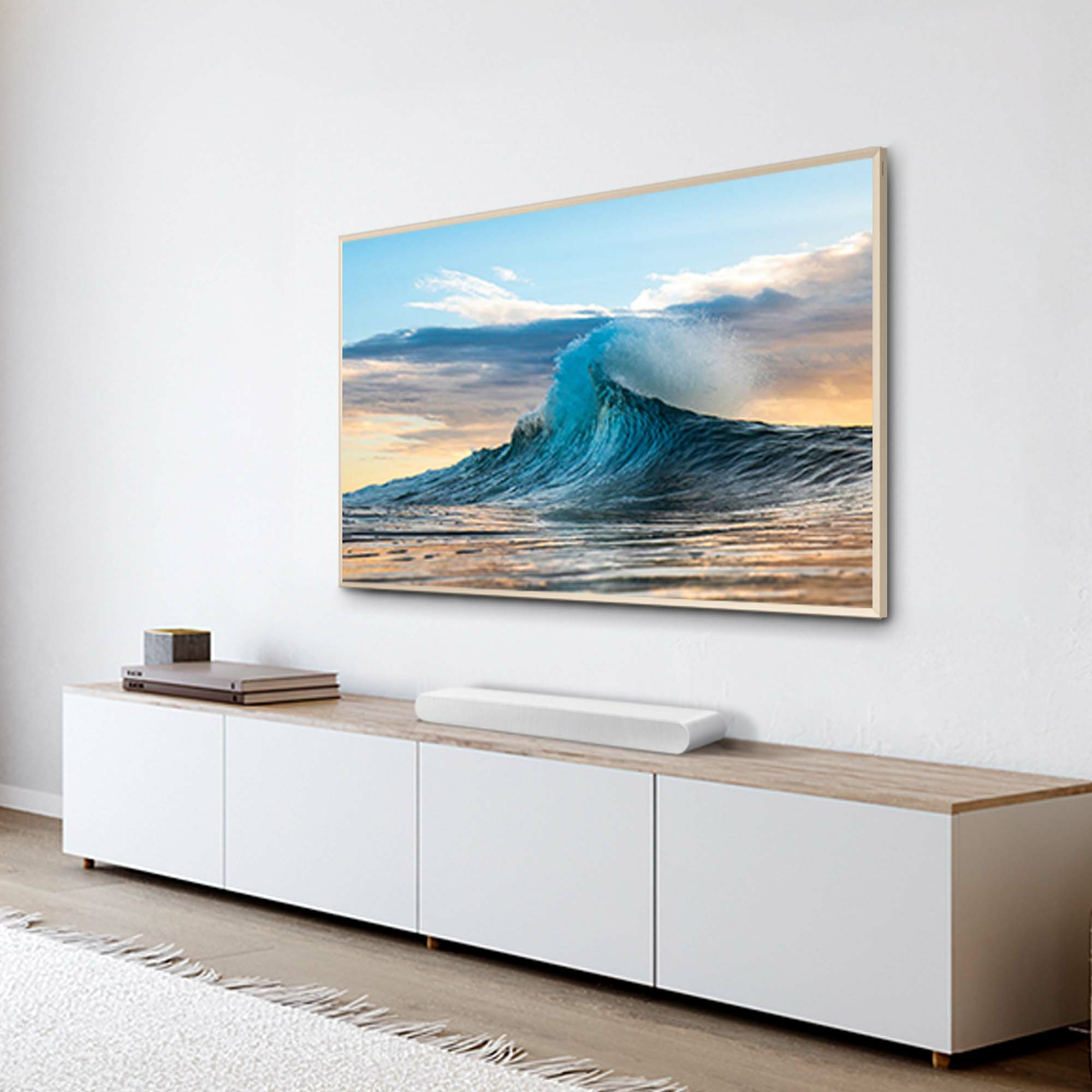 Un téléviseur affichant une vague déferlant sur une plage est monté sur un mur blanc au-dessus d'un meuble.