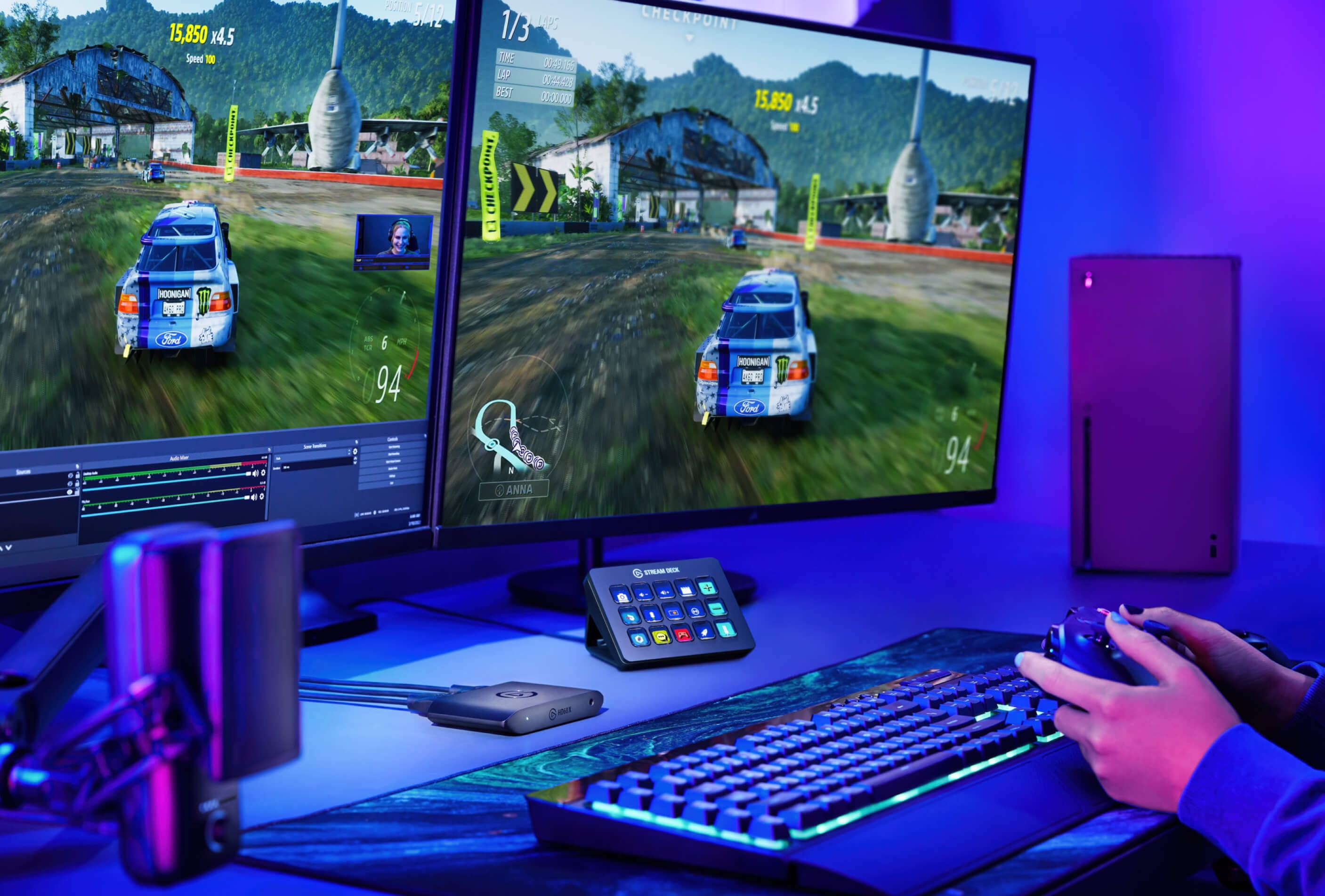 Gracz gra na dwóch monitorach. Gra to gra wyścigowa. Klawiatura, mysz i kontroler na biurku.