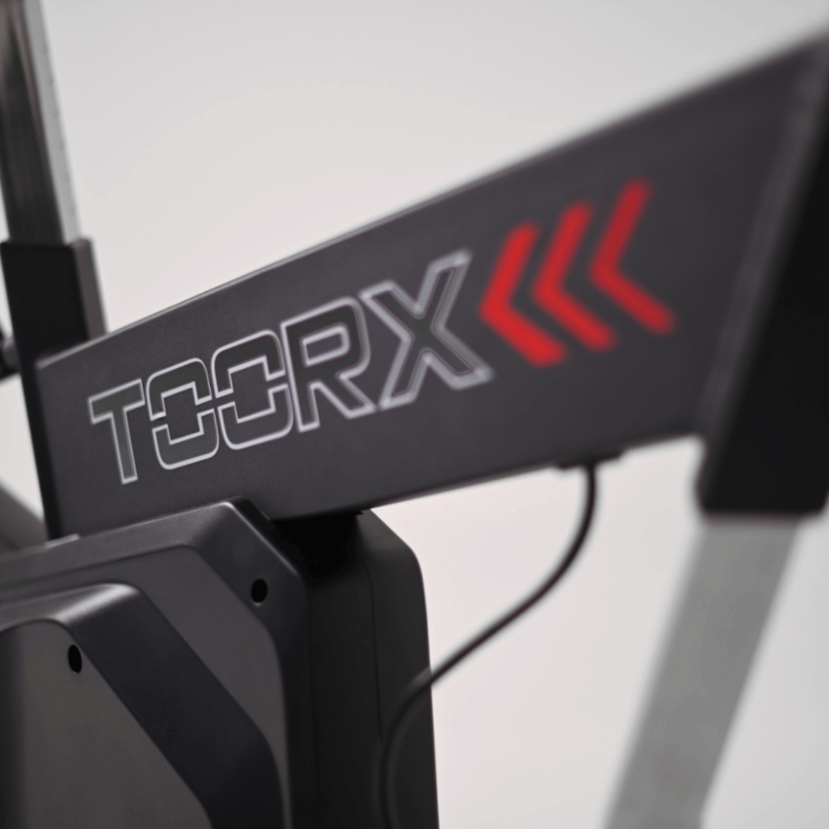 Nahaufnahme einer Fitnessmaschine mit dem Markennamen TOORX. Rote Pfeile sind an der Seite.