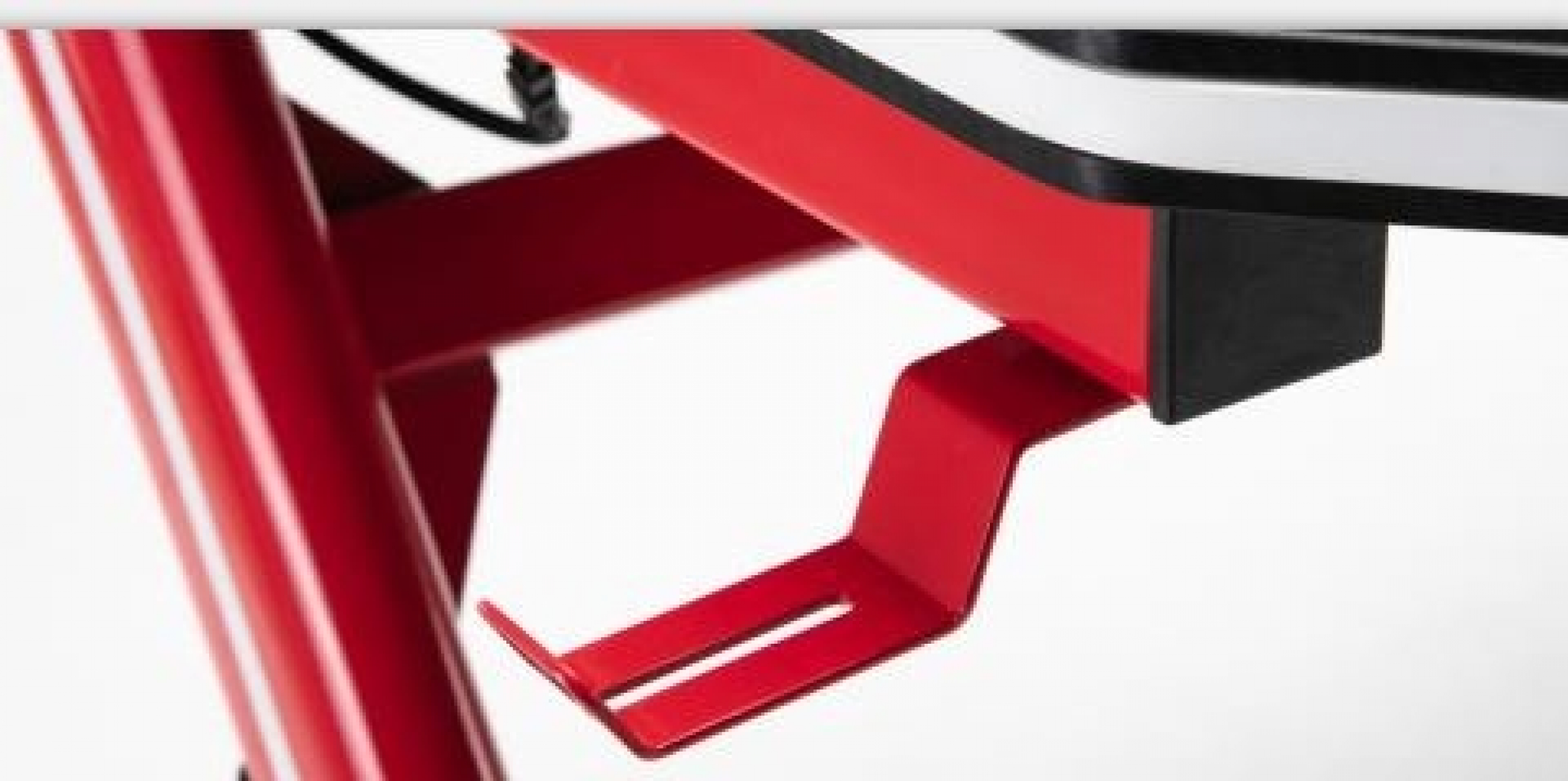 Eine rote Metallhalterung ist an einer größeren Struktur befestigt. Die Halterung hat eine Stütze und einen Aufnahmeschlitz.