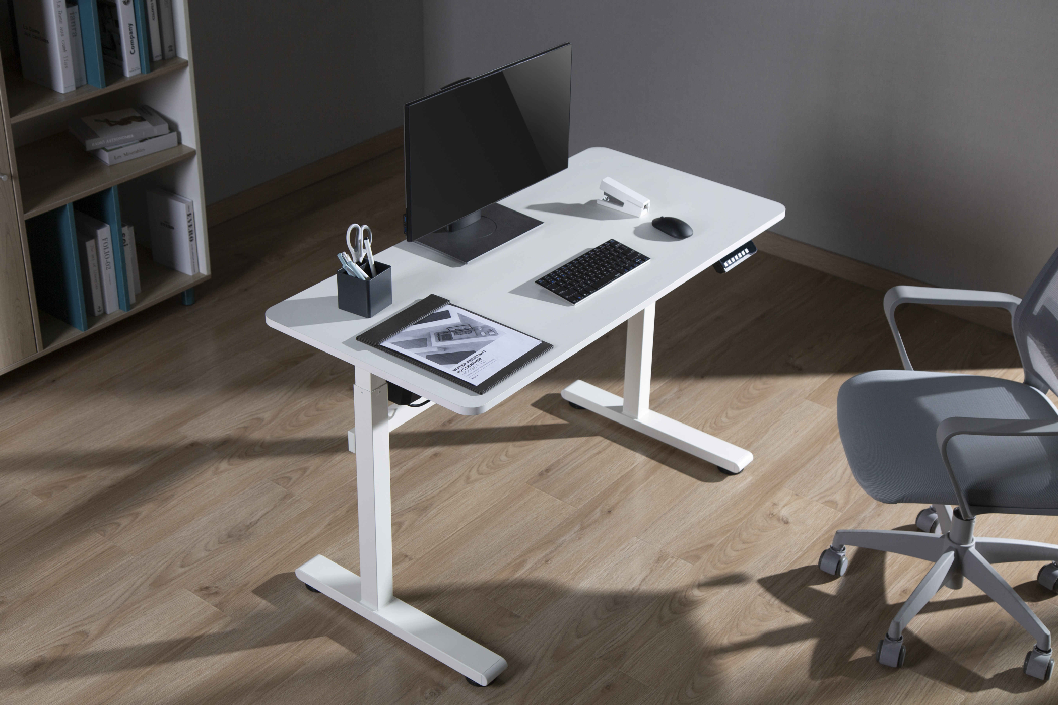 Een witte in hoogte verstelbare bureau met een monitor, toetsenbord en andere kantoorbenodigdheden.