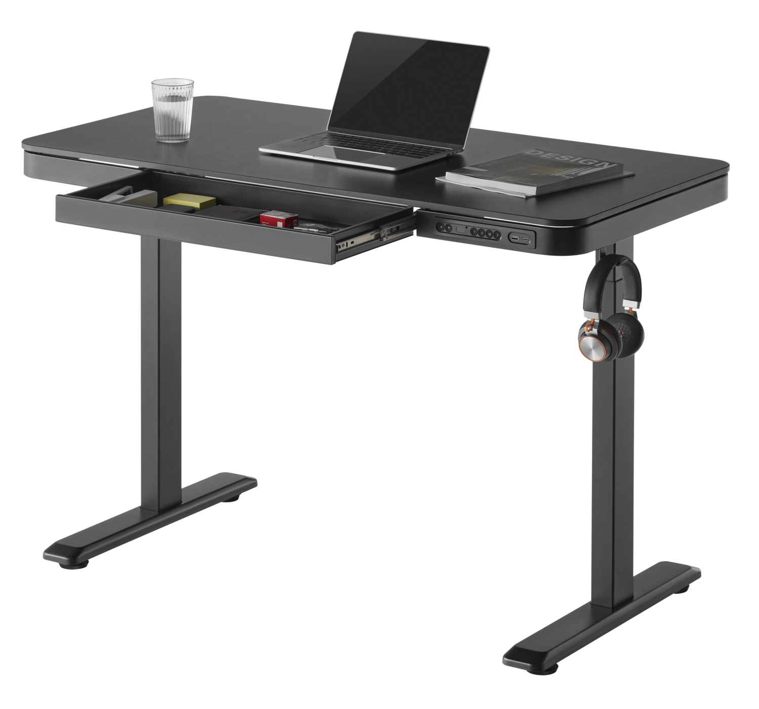 Ein schwarzer, höhenverstellbarer Schreibtisch mit Schublade, Laptop und Kopfhörern. Es gibt ein Glas und ein Buch.