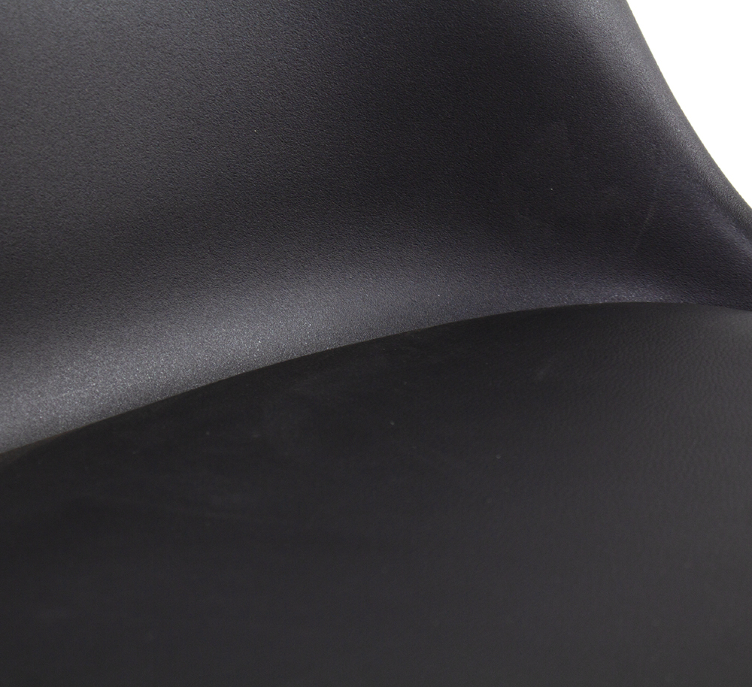 Close-up of a curved black plastic chair. Smooth surface, with soft shadows and curves.