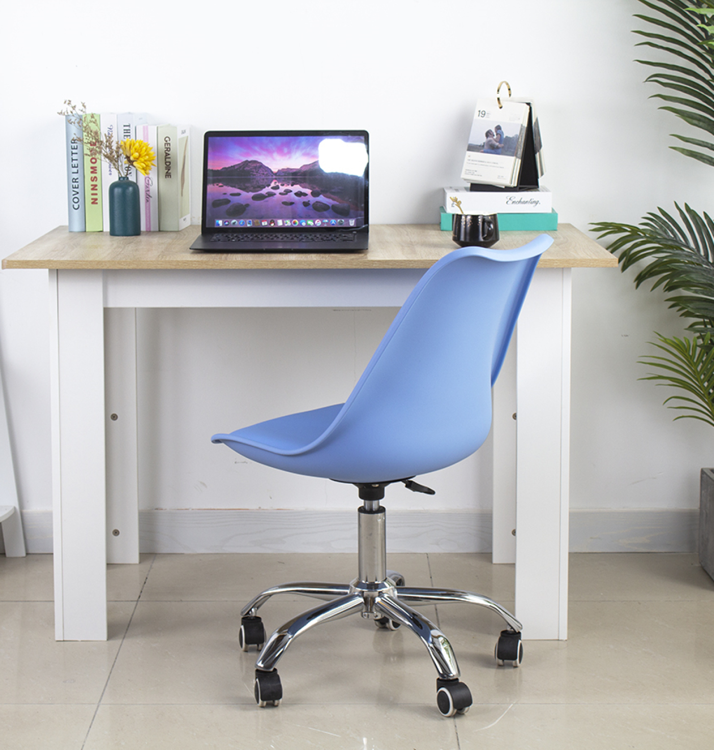 Wooden desk with a blue chair. A laptop, books, and a calendar are on the table.