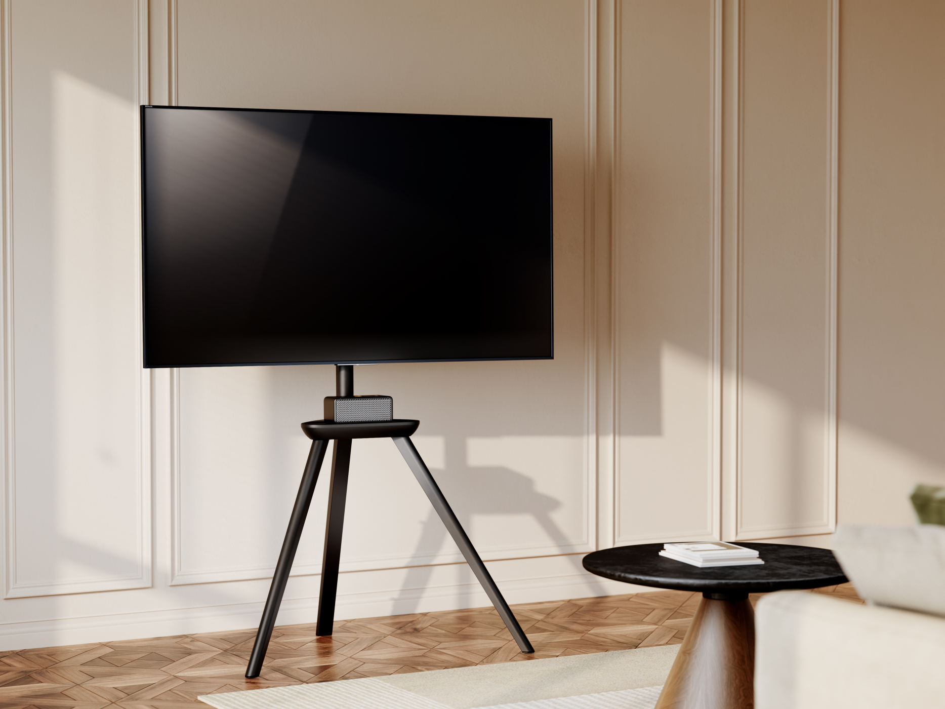 Fernseher auf einem Ständer, mit rundem Tisch und Sofa. Beige Wand und Fenster.