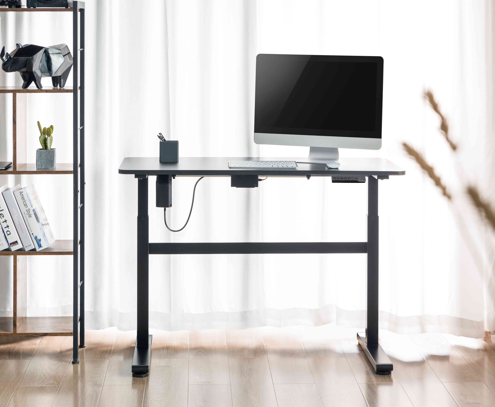Een zwart bureau met een computeropstelling. Inclusief een monitor, toetsenbord en muis, met een boekenplank.