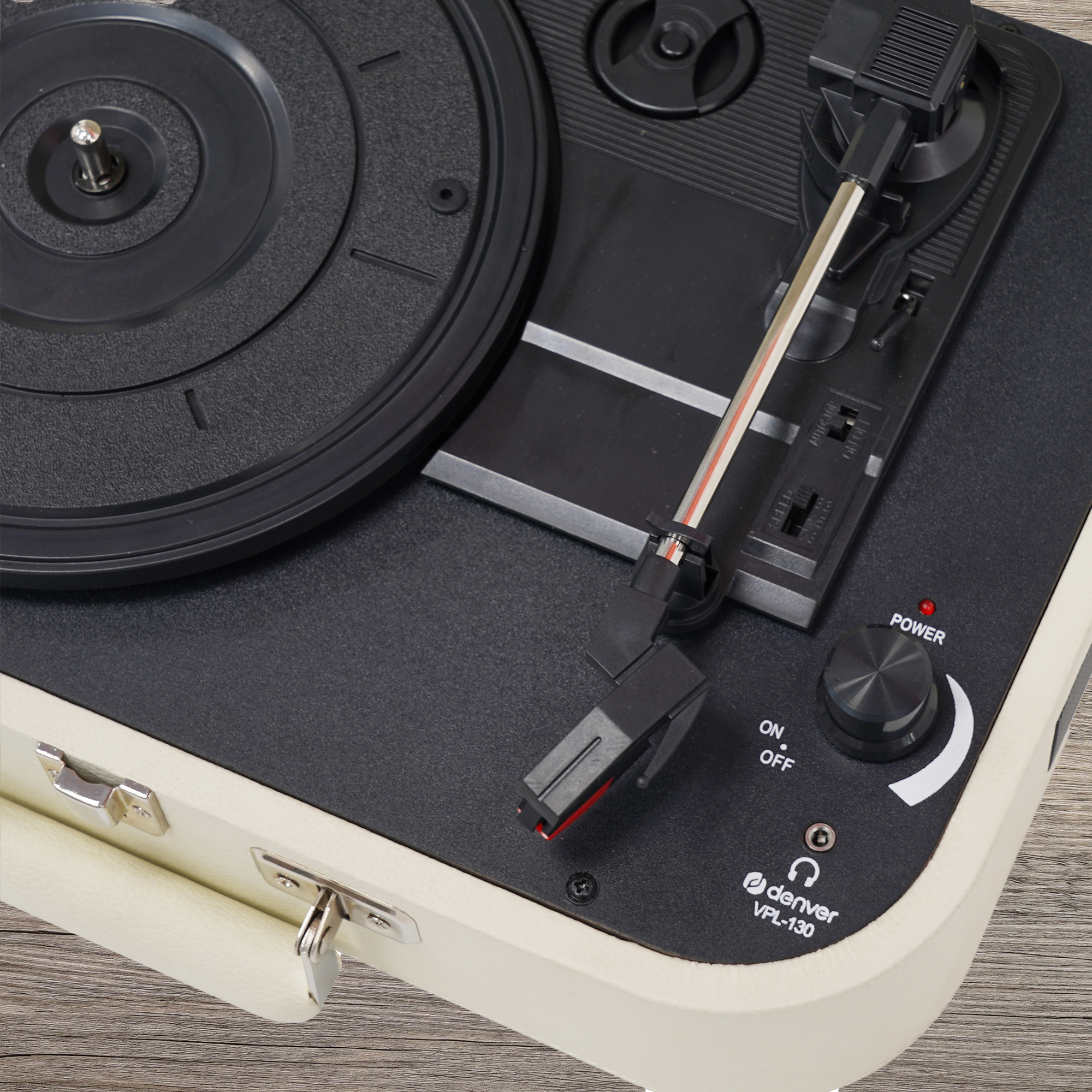 Gramofon stoi na drewnianej powierzchni. Ramię nad czarną płytą winylową.