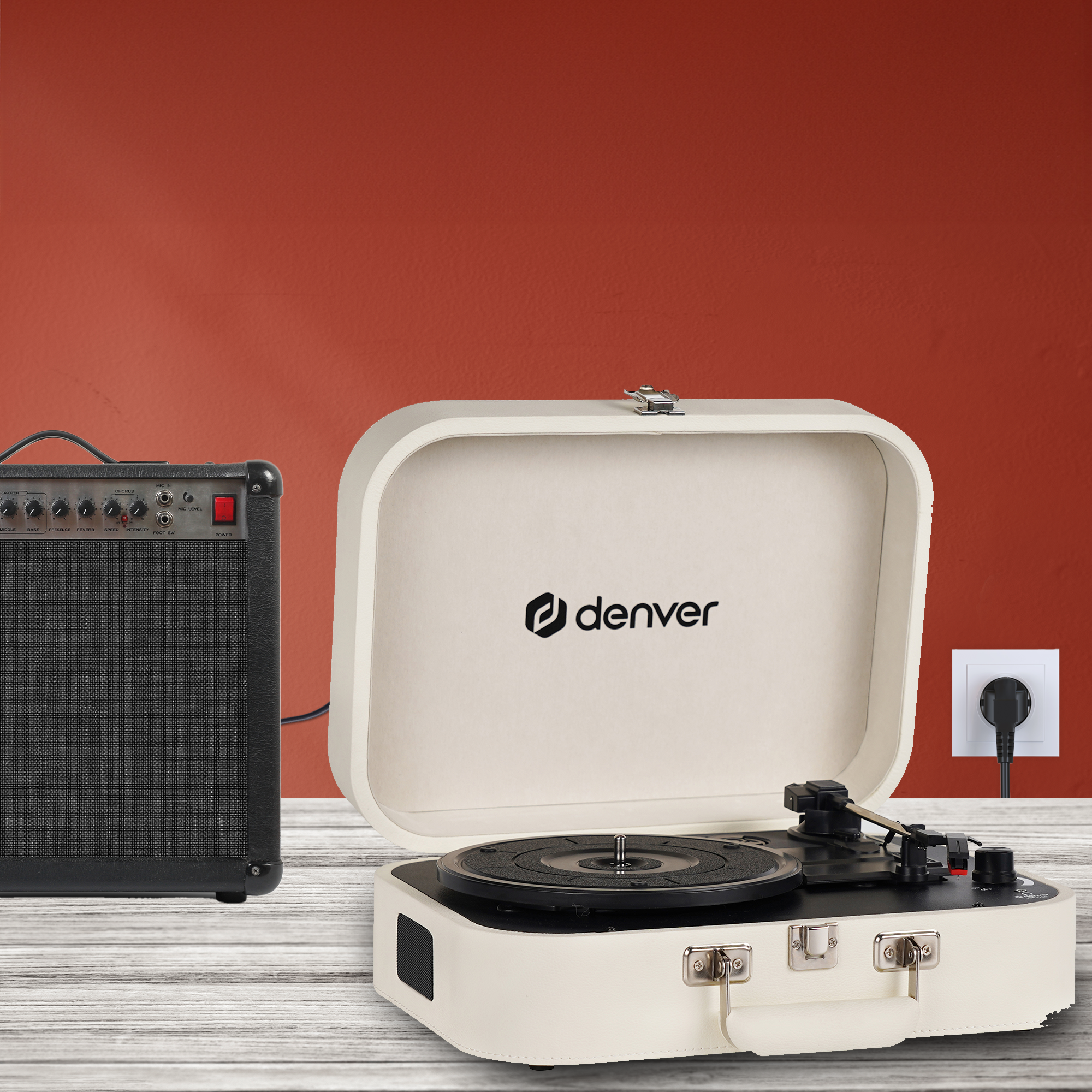 Gramofon w białej walizce obok wzmacniacza. Tło jest czerwone.