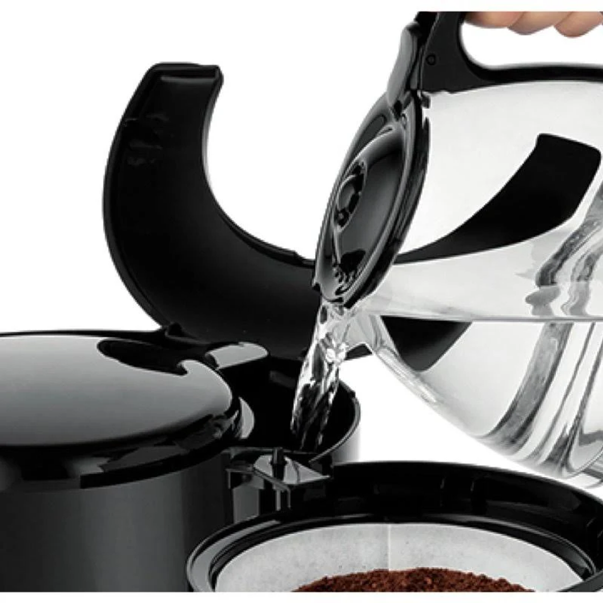 Zbliżenie wody wlewanej do ekspresu do kawy, widoczne fusy.