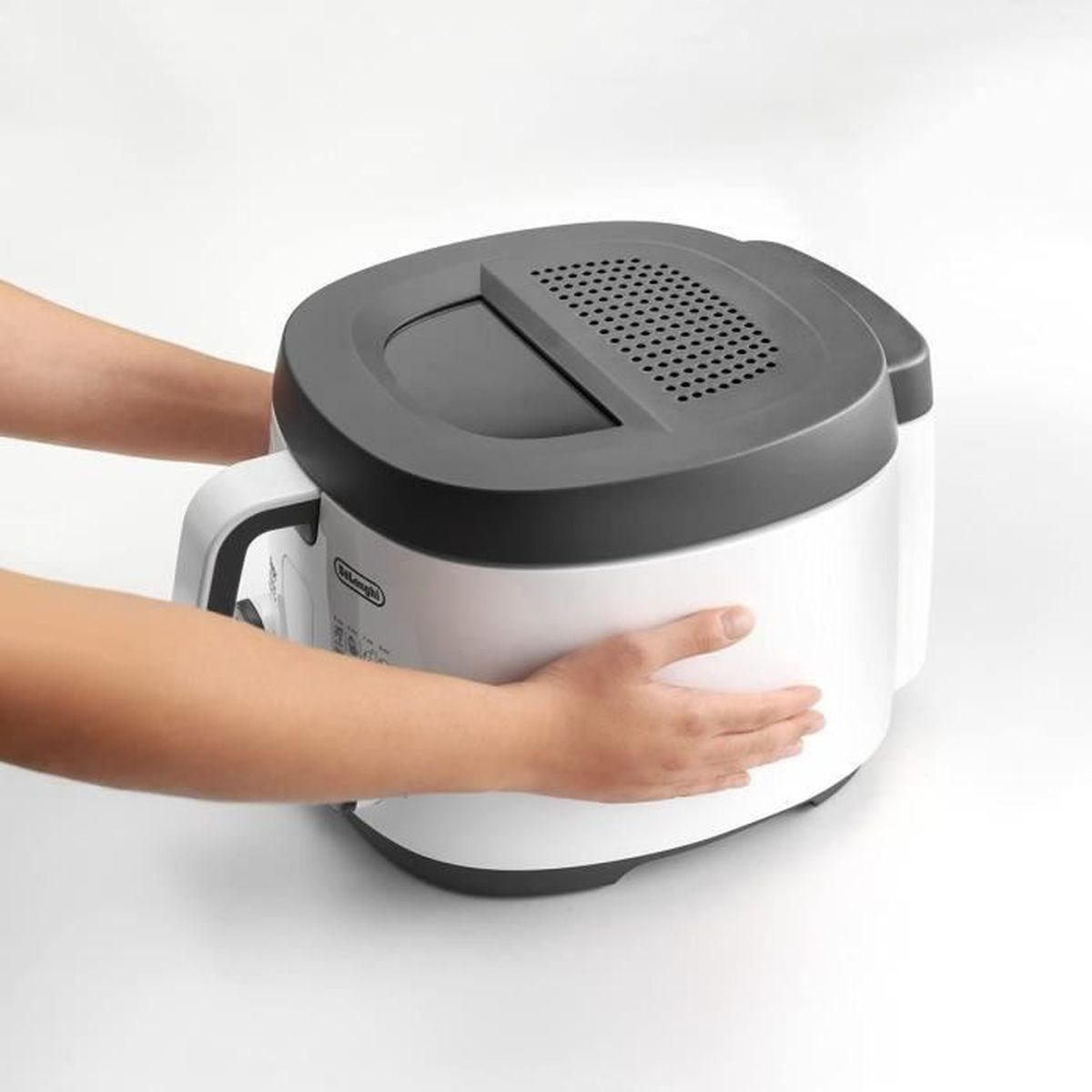 Biało-czarna frytkownica. Ręce trzymające frytkownicę. Białe tło.