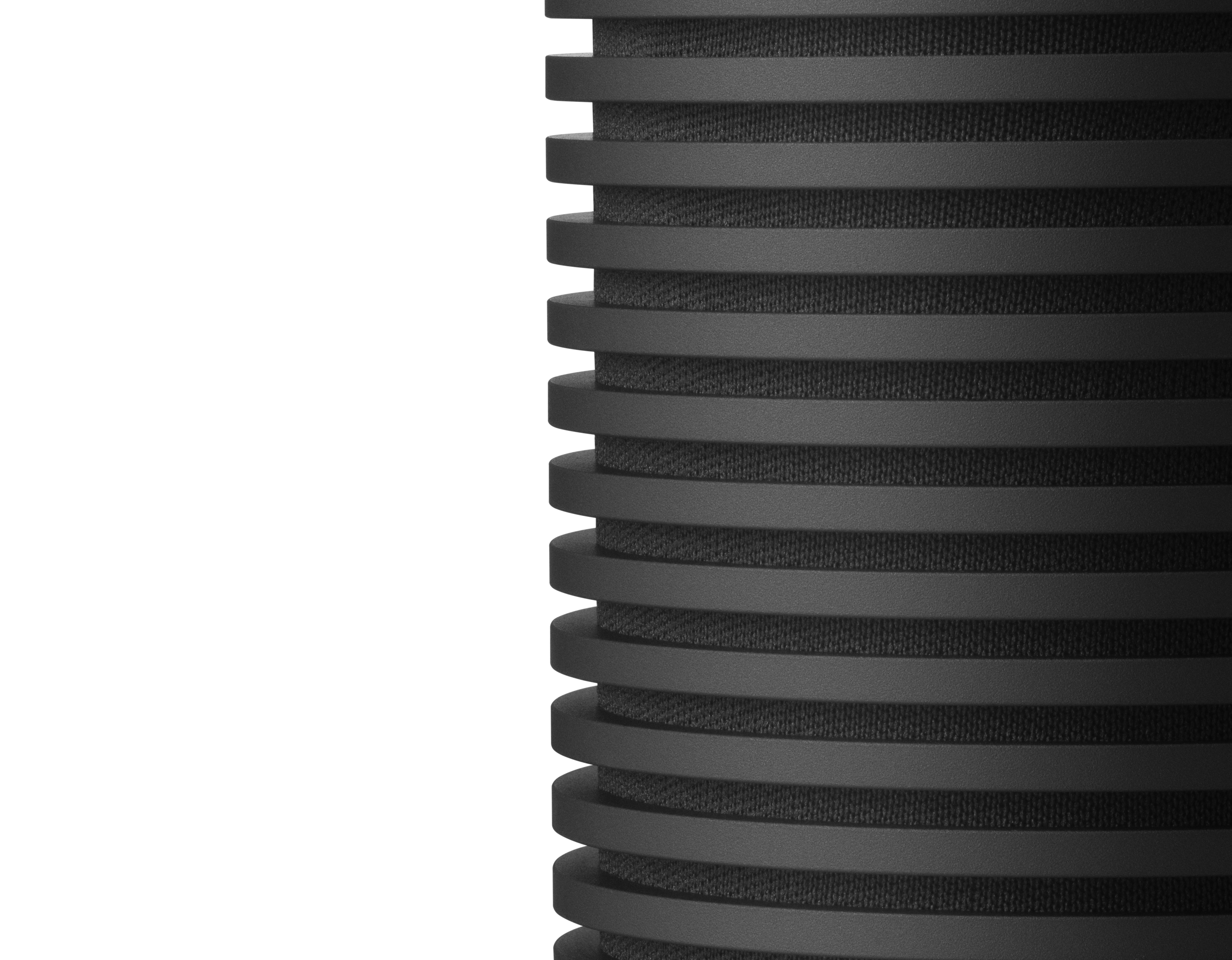 Zbliżenie na bok czarnego głośnika z poziomymi rowkami, na białym tle.