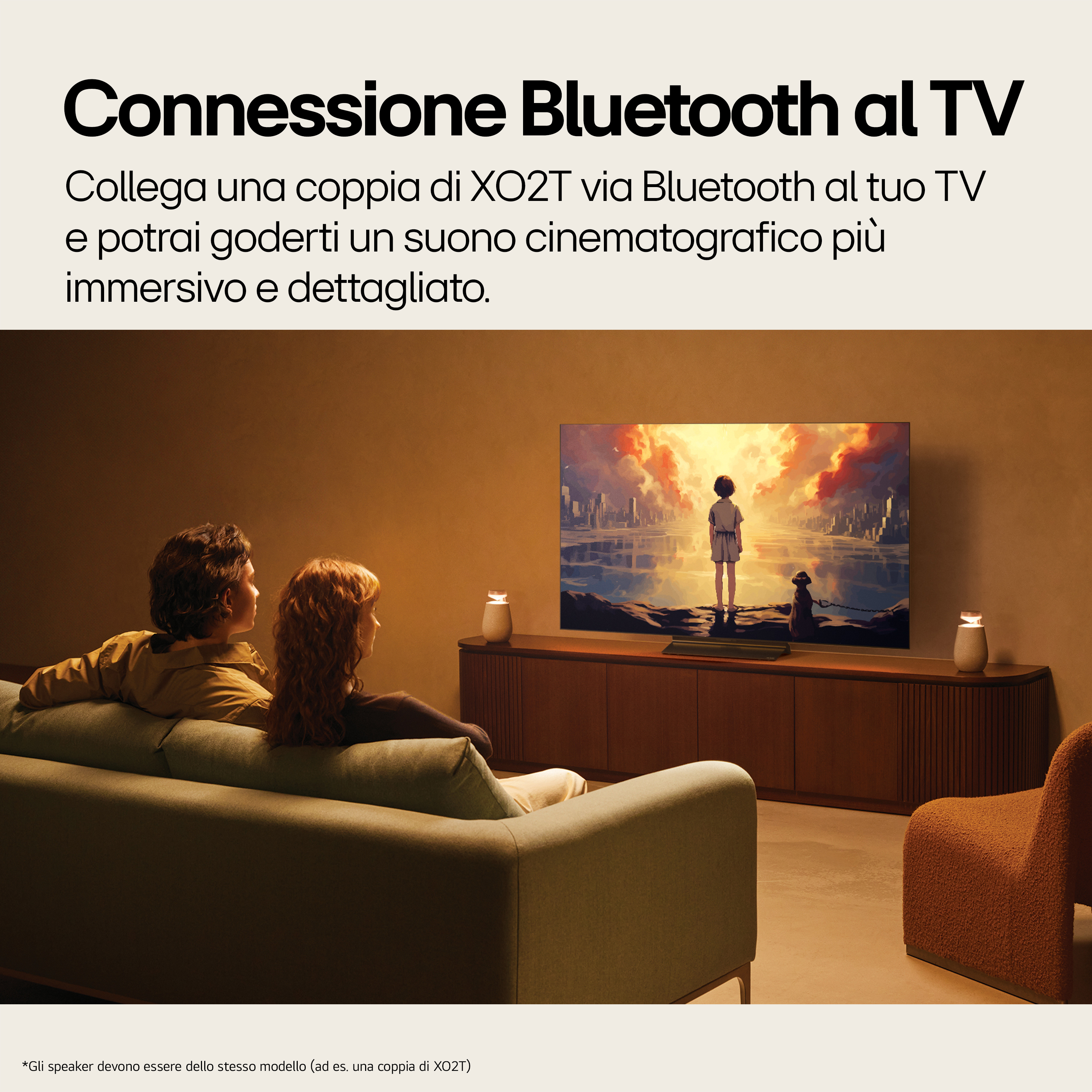 Een stel zit op een bank en kijkt tv. Er staan luidsprekers aan weerszijden van de tv.