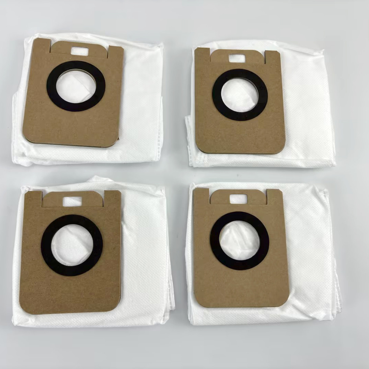 Cztery worki do odkurzacza. Każdy ma brązowy kartonowy przód z czarnym gumowym pierścieniem.