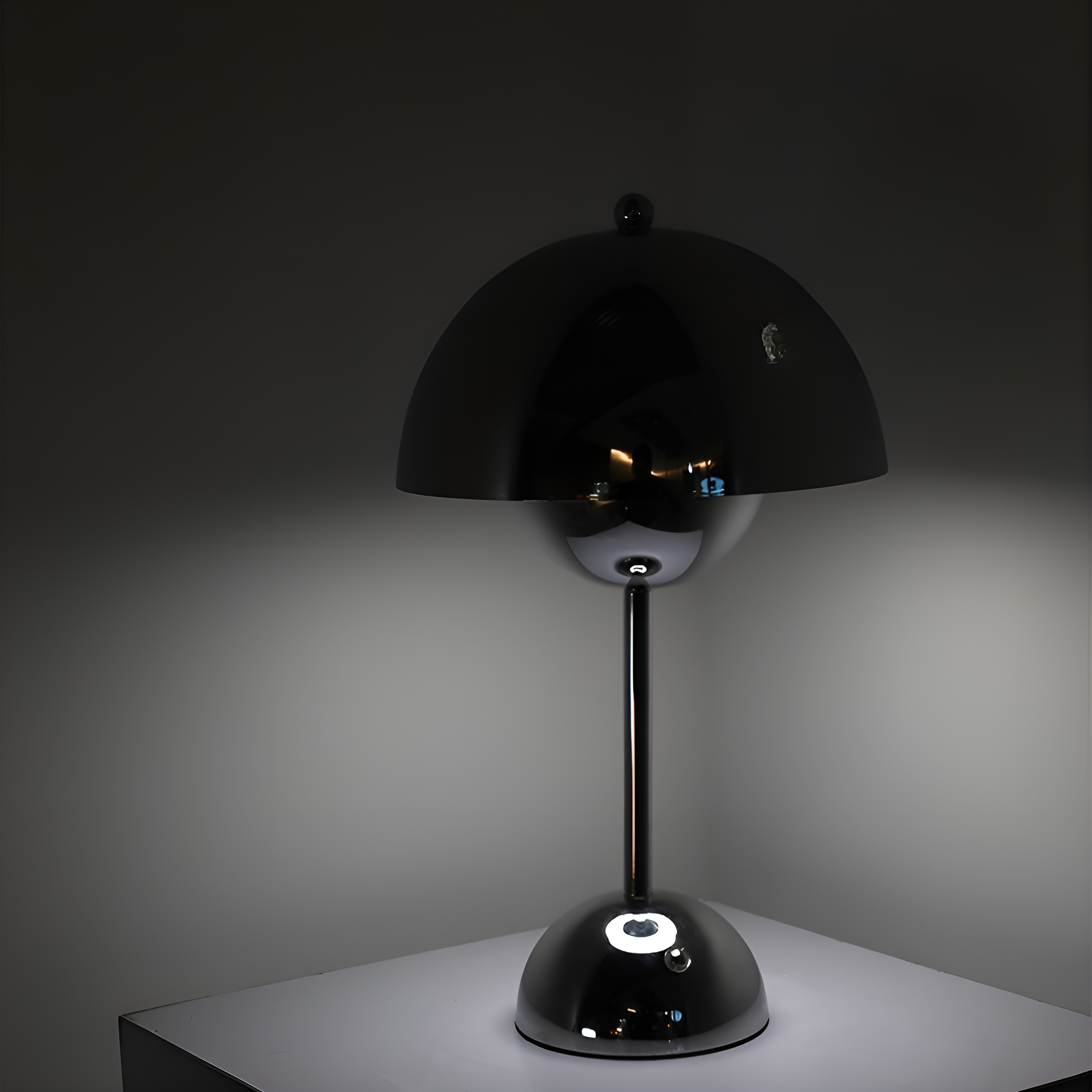 Eine moderne schwarze Lampe mit rundem Schirm und metallischem Fuß, auf einer weißen Oberfläche.