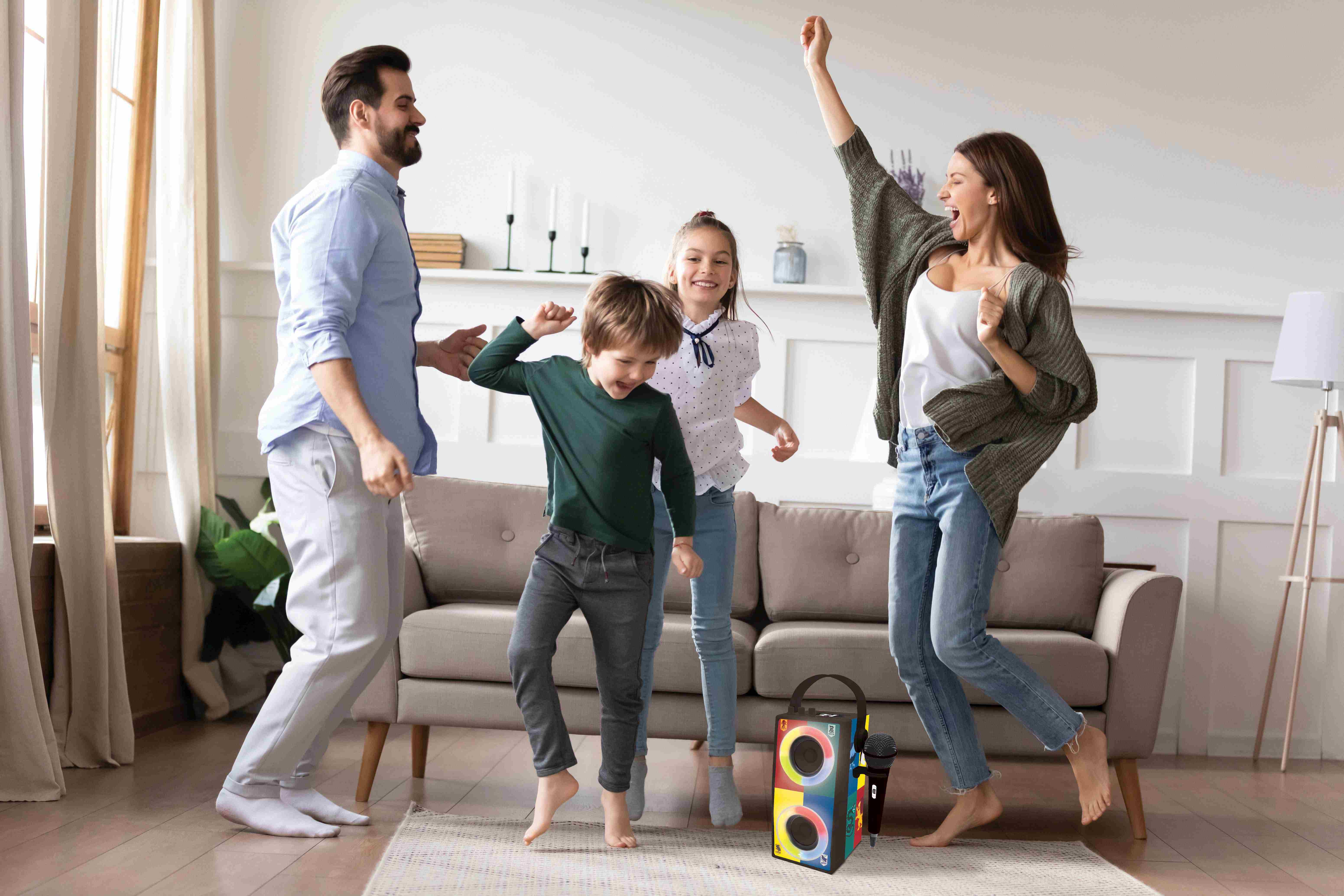 Una familia bailando en una sala de estar con un altavoz y un micrófono. Ambiente alegre.