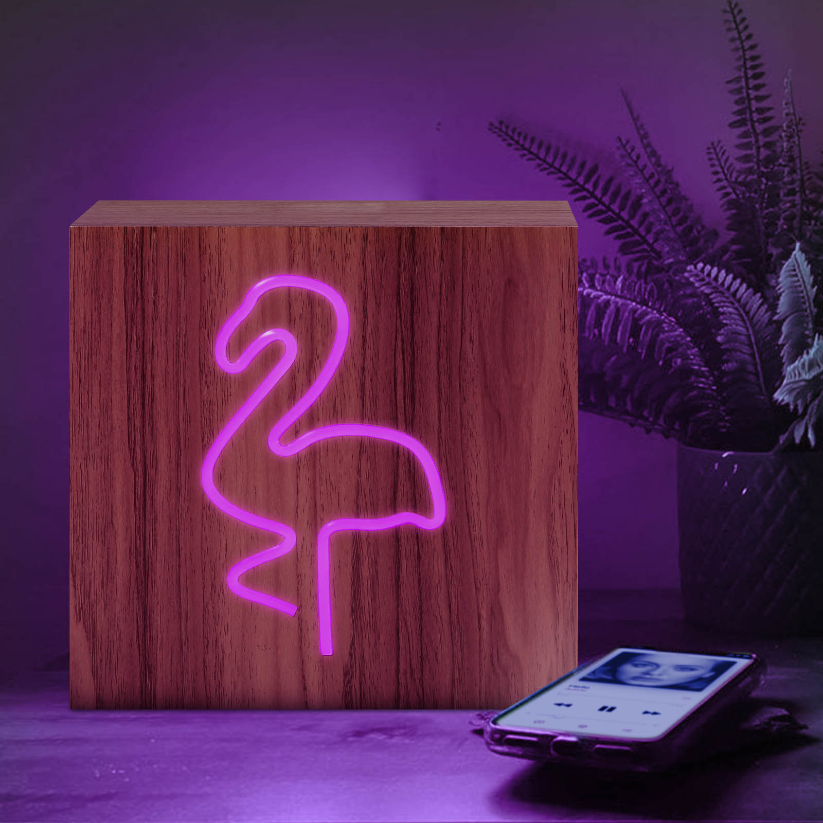 Une lampe en bois avec un signe néon de flamant rose. Un téléphone est sur la table.