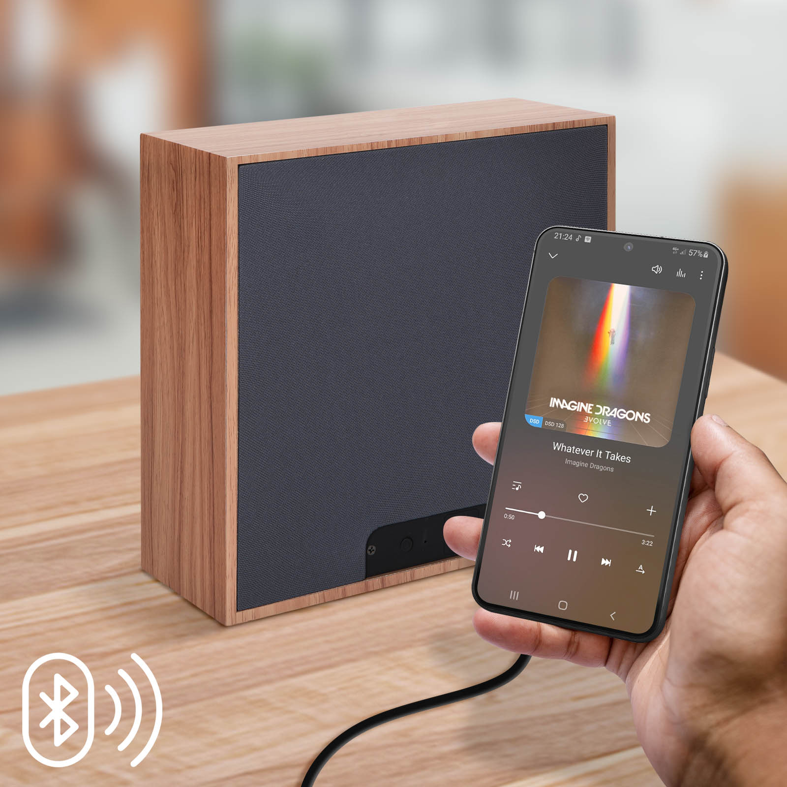 Haut-parleur en bois à côté d'un téléphone jouant de la musique, connecté par câble. Icône Bluetooth.