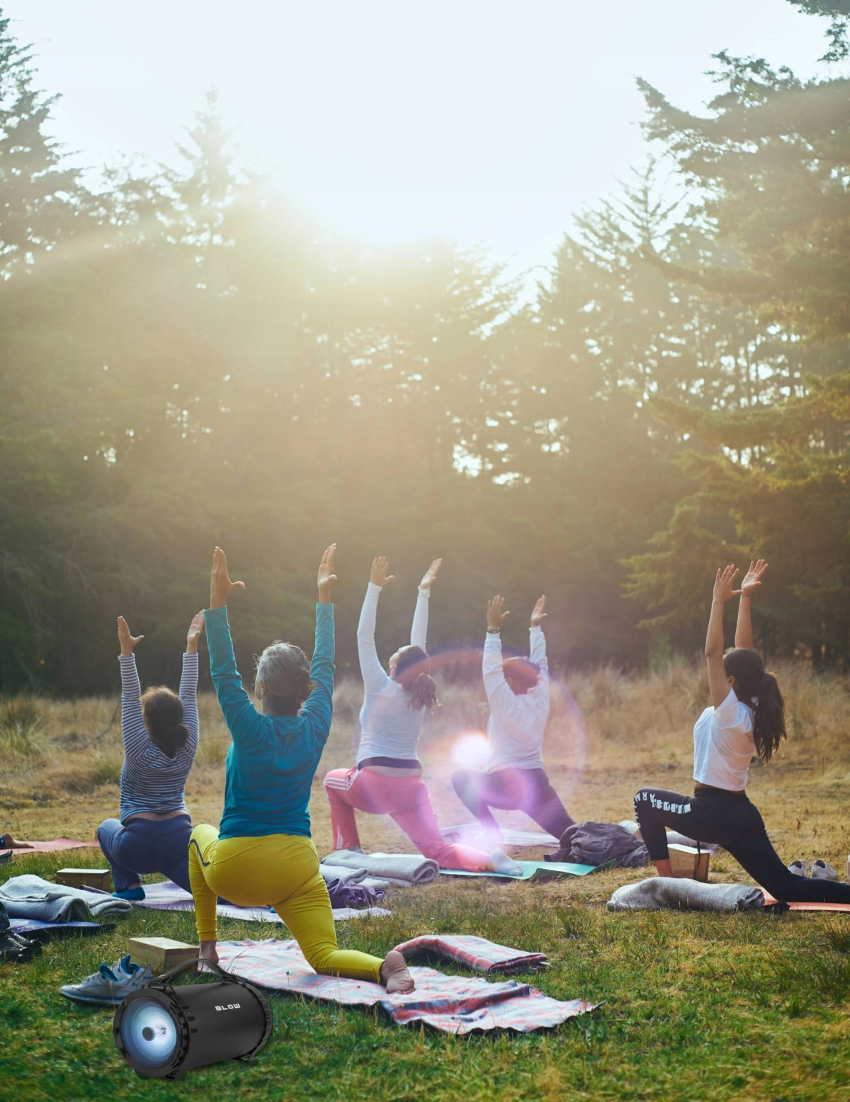 Ludzie uprawiający jogę w lesie z projektorem z przodu.