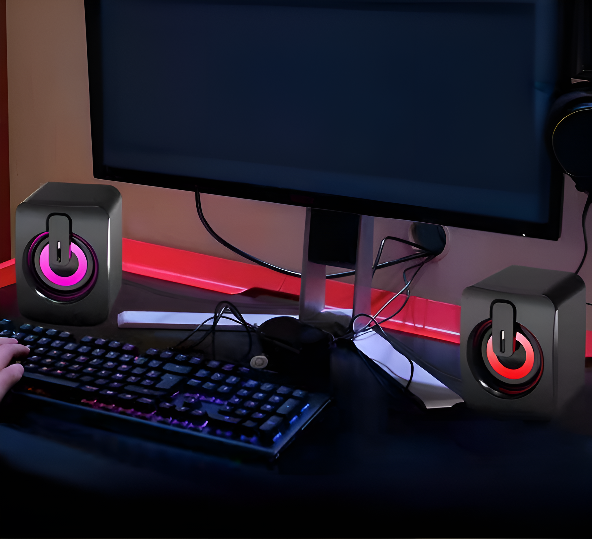 Paar schwarze Lautsprecher mit rosa und roten Lichtern und eine Tastatur.
