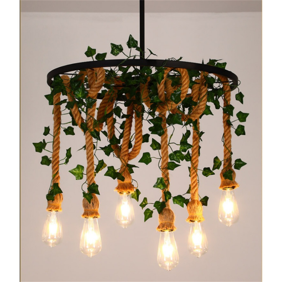 Ein Kronleuchter mit Seil, Blättern und Glühbirnen. Er hängt von der Decke und die Lichter sind an.