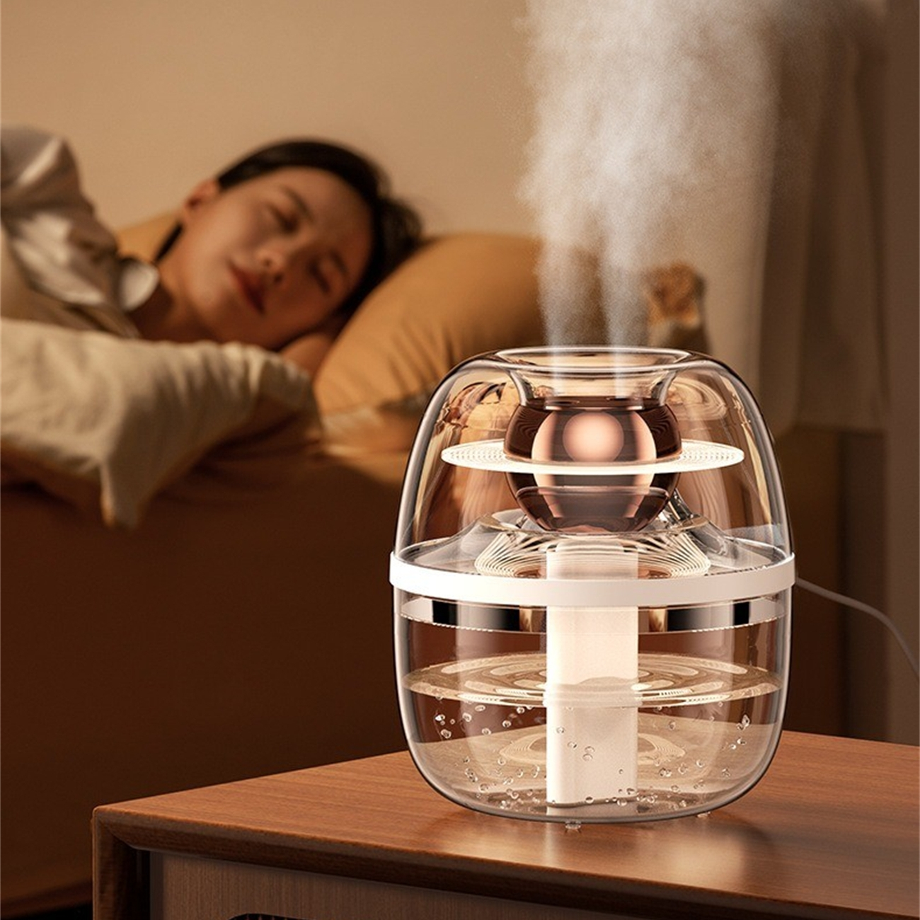 Transparenter Luftbefeuchter mit Dampf. Schlafende Frau im Hintergrund. Holztisch. Weiche Beleuchtung.