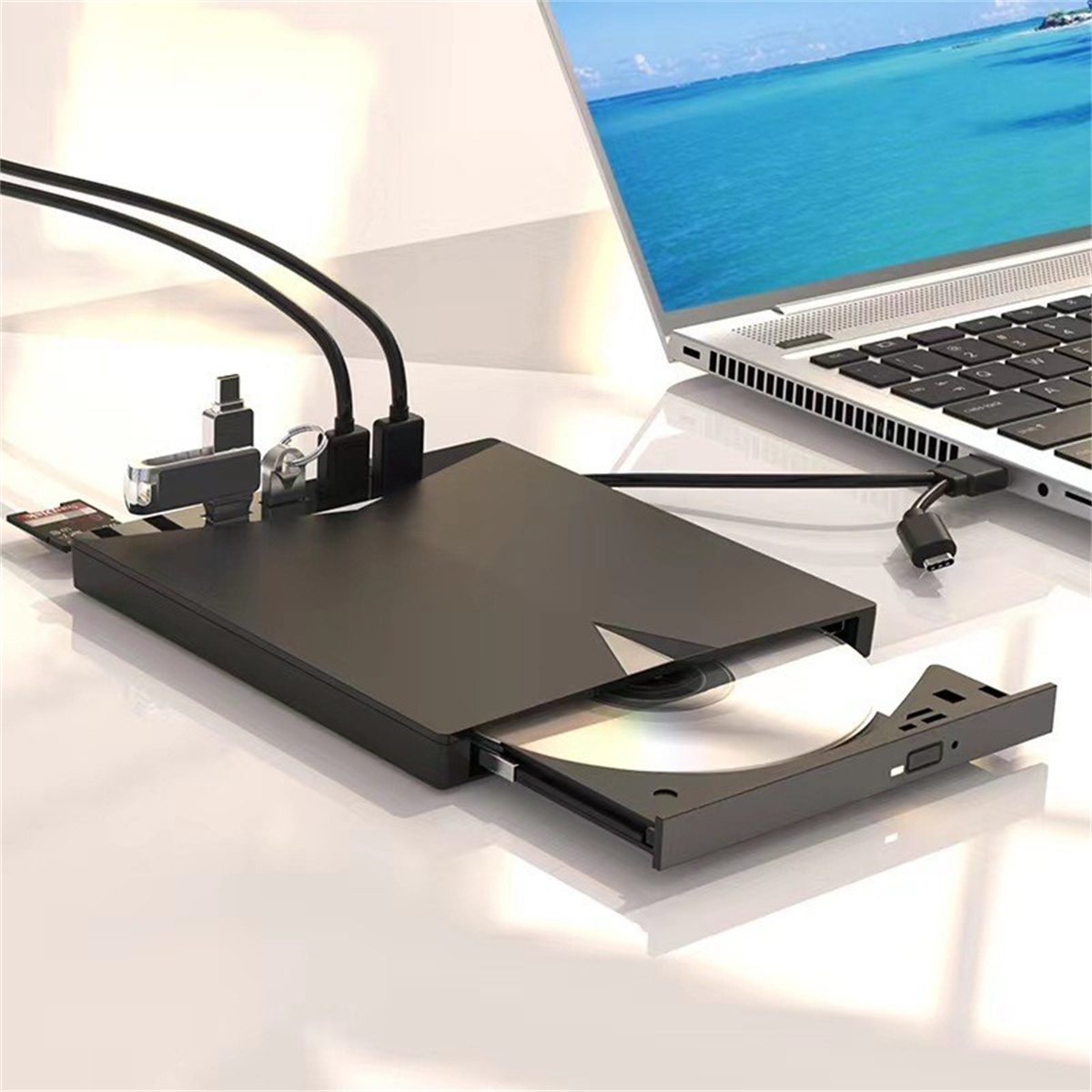 Schwarzes externes CD/DVD-Laufwerk, über Kabel mit einem Laptop verbunden.
