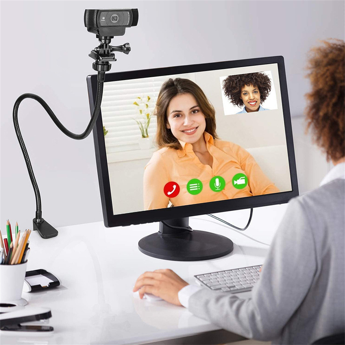Person verwendet Webcam, angeschlossen an einen Computerbildschirm, der einen Videoanruf mit einer Frau zeigt.