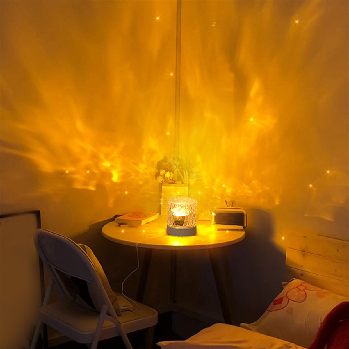 Eine Tischlampe mit sternförmiger Projektion an der Wand. Auf dem Tisch liegen Bücher und Dekorationen.